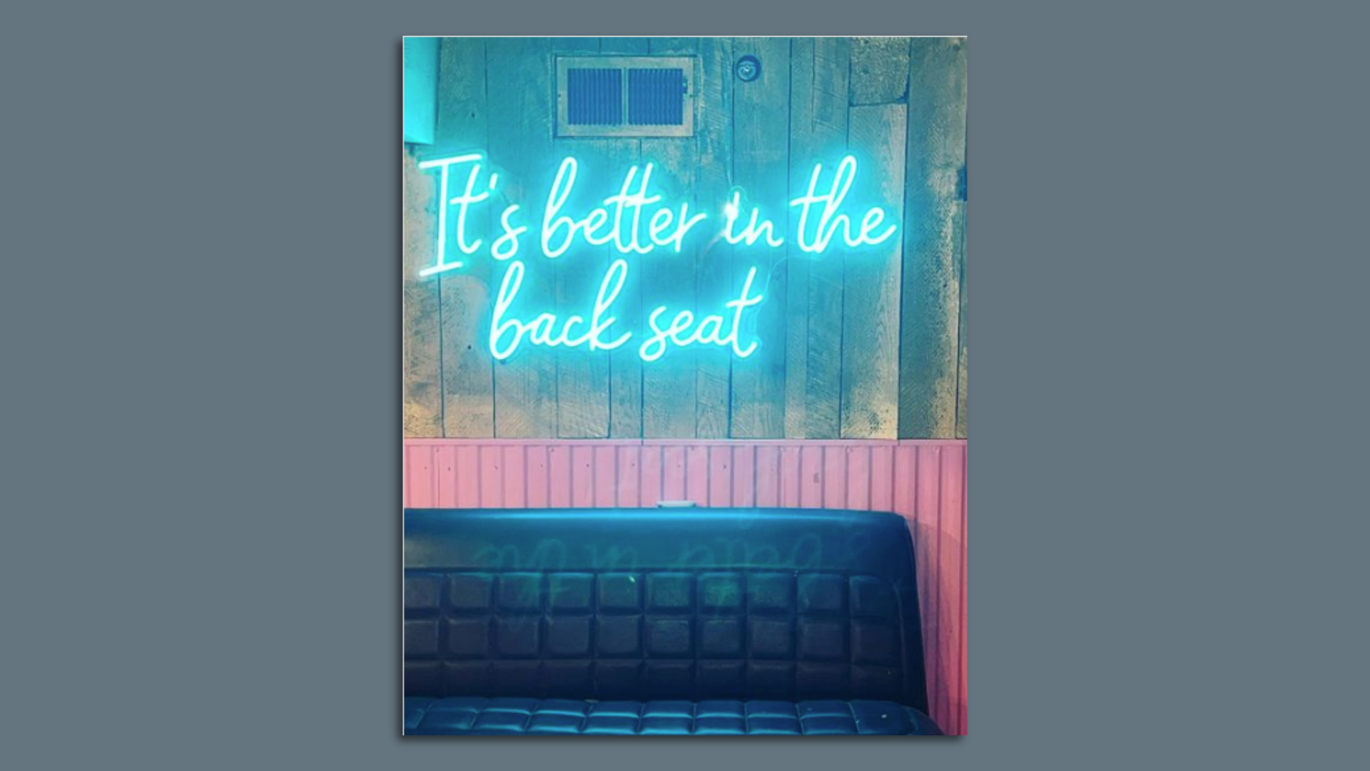 A restaurant booth that says it's better in the back seat over it in neon.