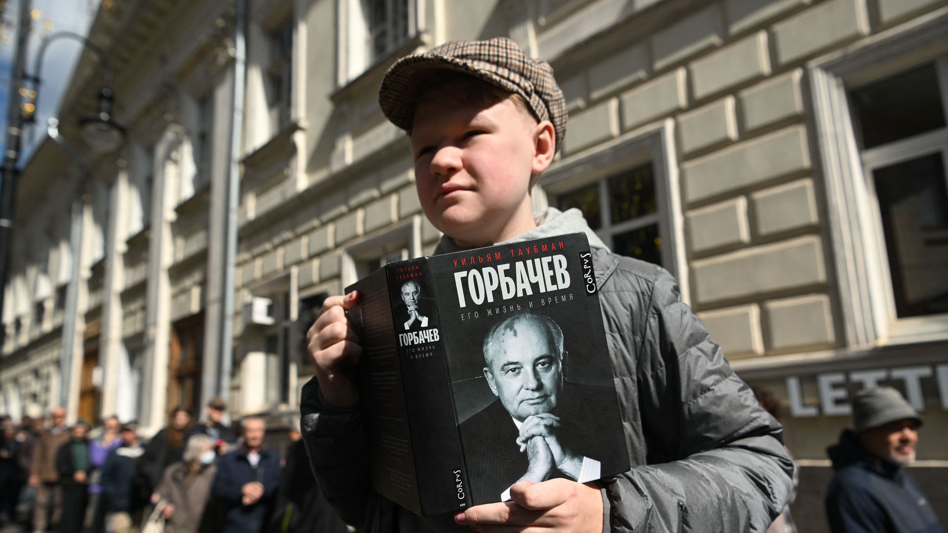 A man holds a book with Mikhail Gorbachev portrait.