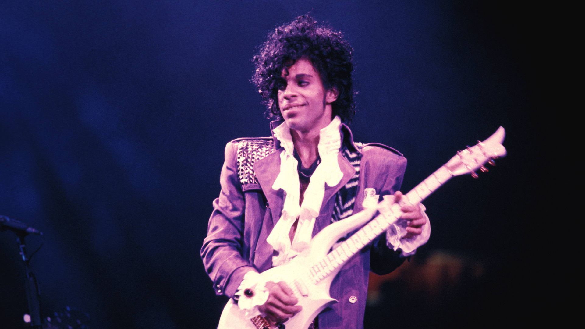 The musician Prince on stage holding a guitar.