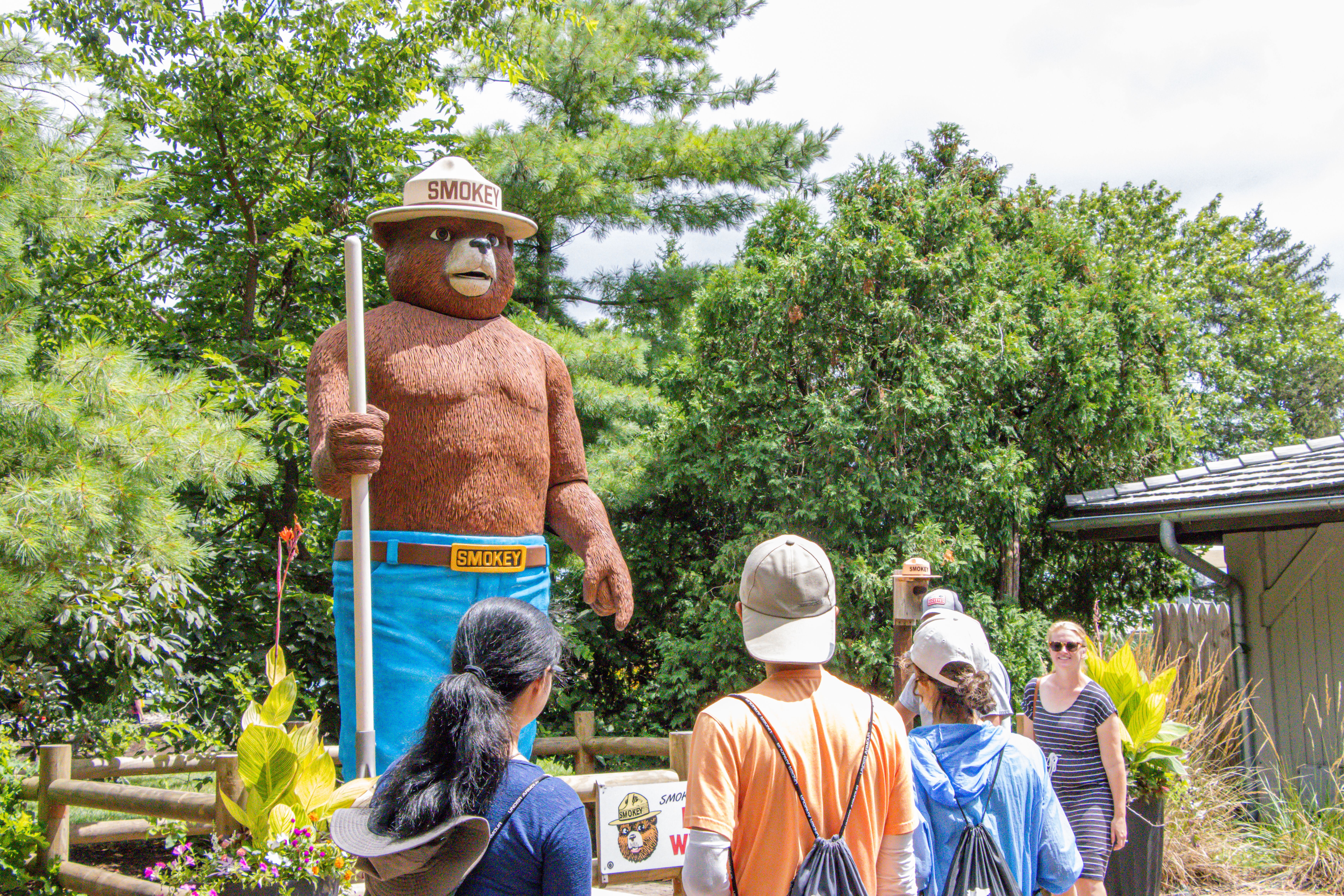 Guests at the Ohio State Fair stand near a large depiction of Smoky the Bear. 