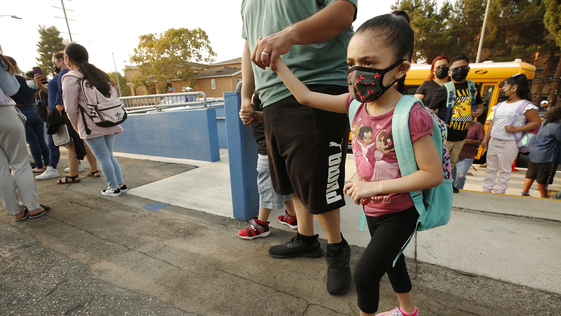 Kindergarten student holds the hand of her father as he walks her to school
