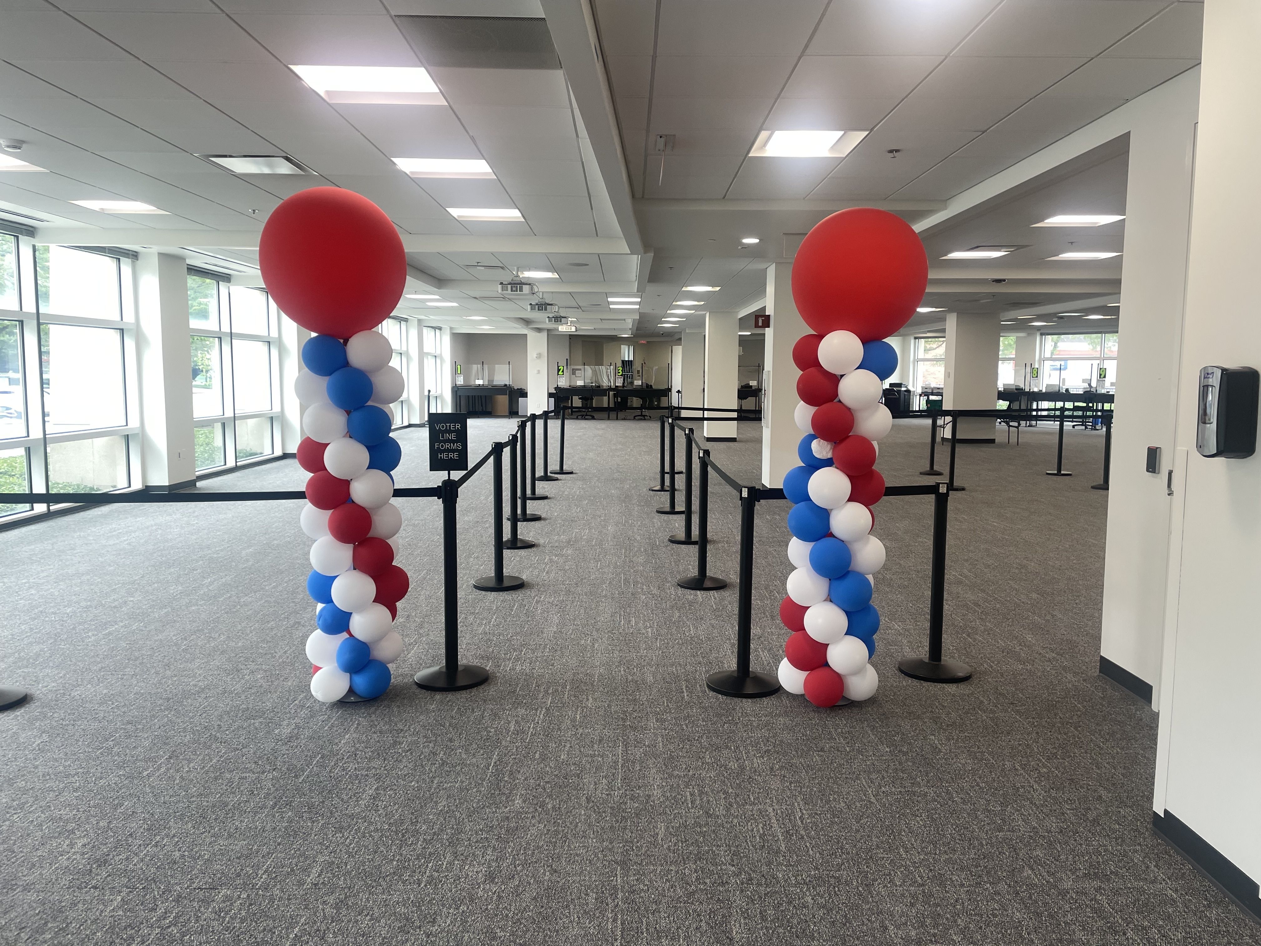 Indoor room with balloons and stanchions for line