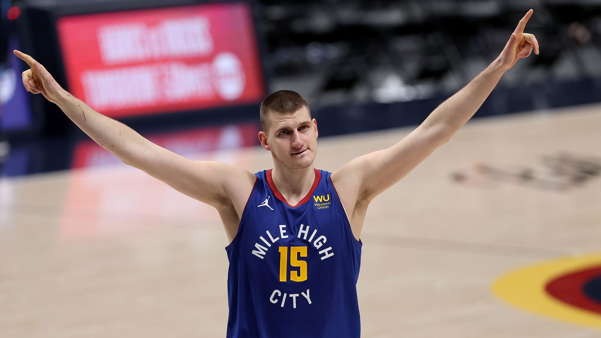 A photo of Nikola Jokic on the basketball court raising his arms in celebration 