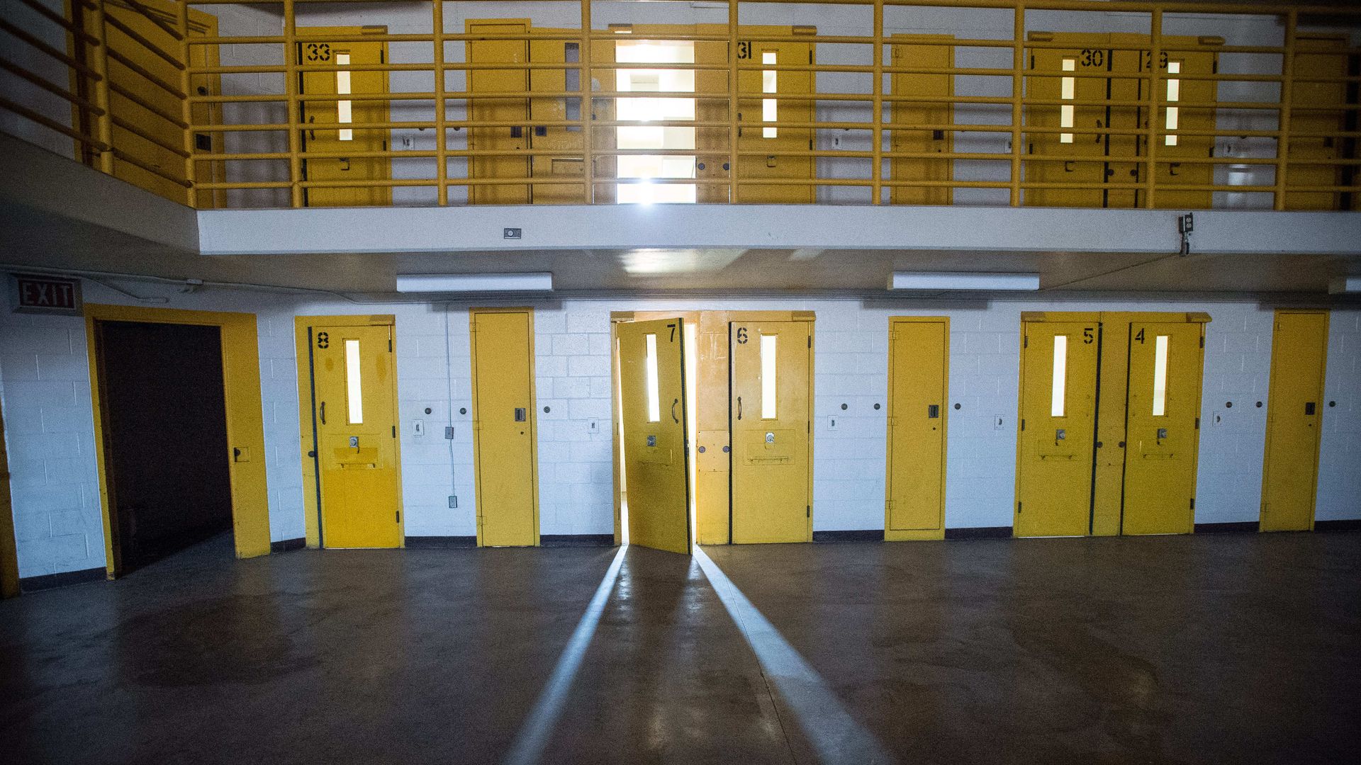 Photo of a former state correctional facility, showing cells with yellow doors 