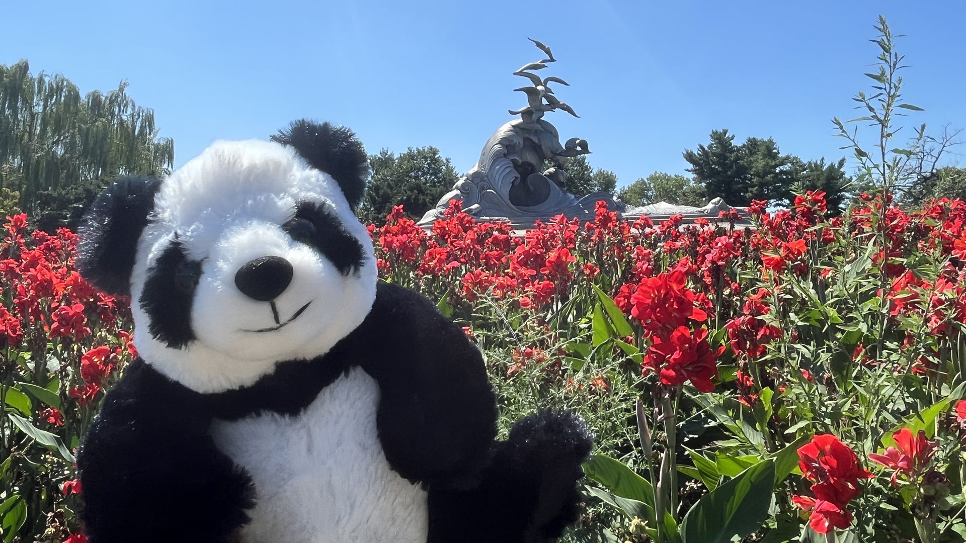 Go-Go smiles in front of red flowers and the Navy Memorial in Lady Bird Johnson Park.