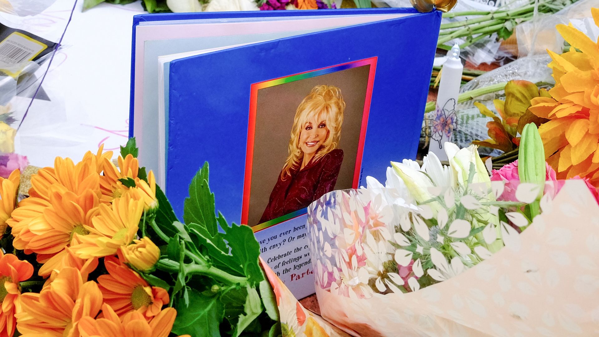Flowers surround a blue hardcover book that bears a photo of Dolly Parton.