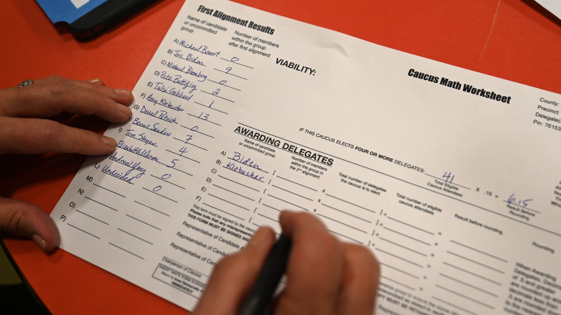 An Iowa caucus volunteer fills out paperwork with Joe Biden and Amy Klobuchar's names on it
