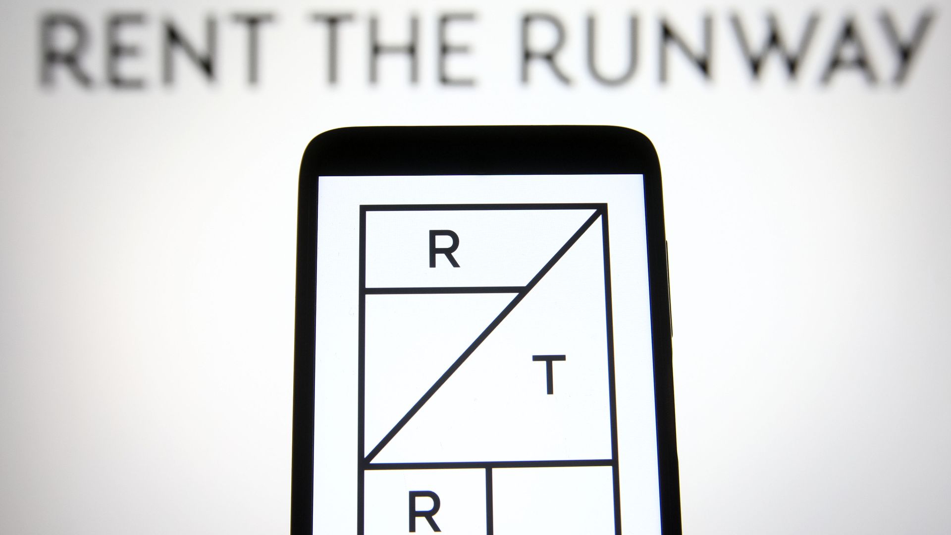 In this photo illustration a Rent the Runway (RTR) logo is seen on a smartphone and a pc screen.