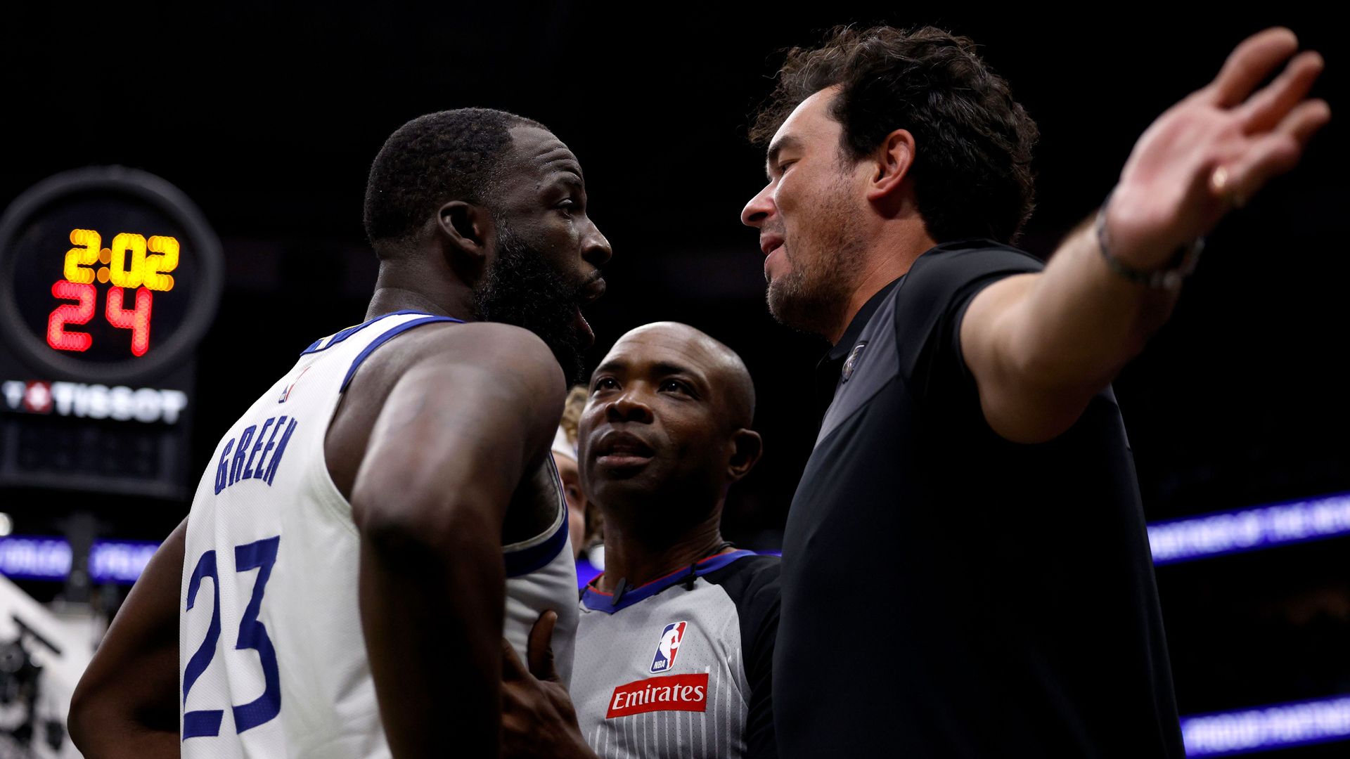 A person wearing a No. 23 jersey that says "Green" approaches a man in a black shirt whose arms are oustretched.