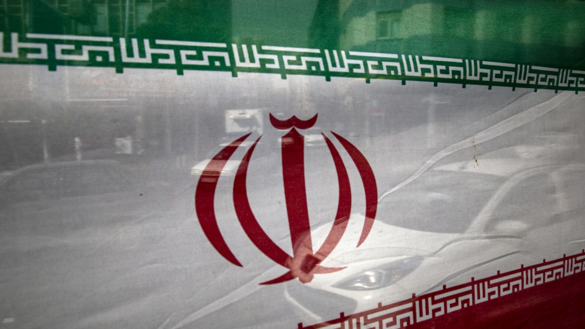 Vehicles are driving past an Iranian flag in downtown Tehran, Iran, on February 28, 2024.
