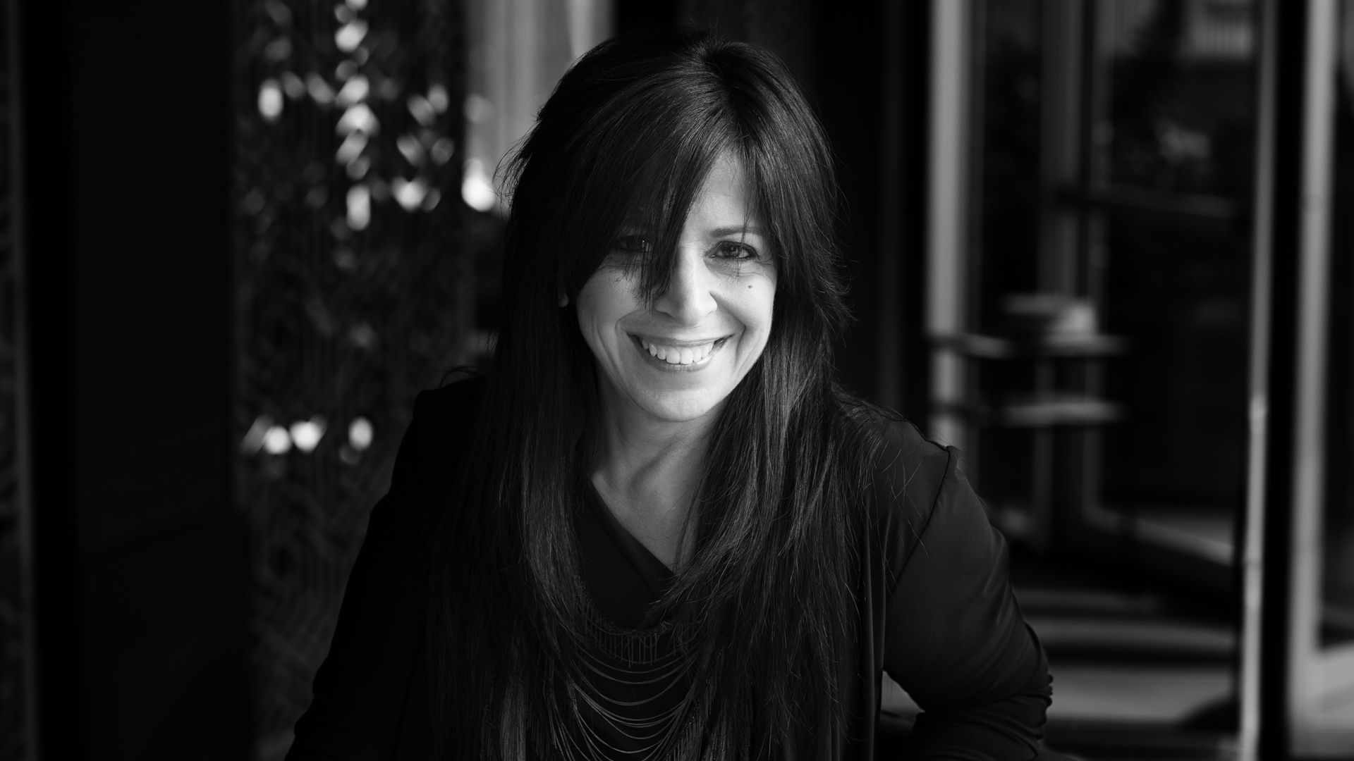 Black and white photo of woman with dark, long hair, smiling.