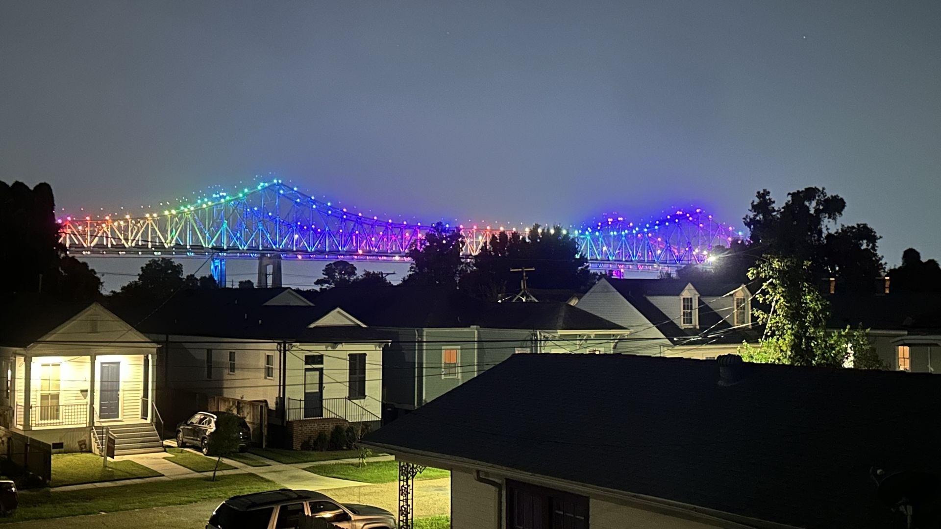 The Crescent City Connection is lit in rainbow lights at night.