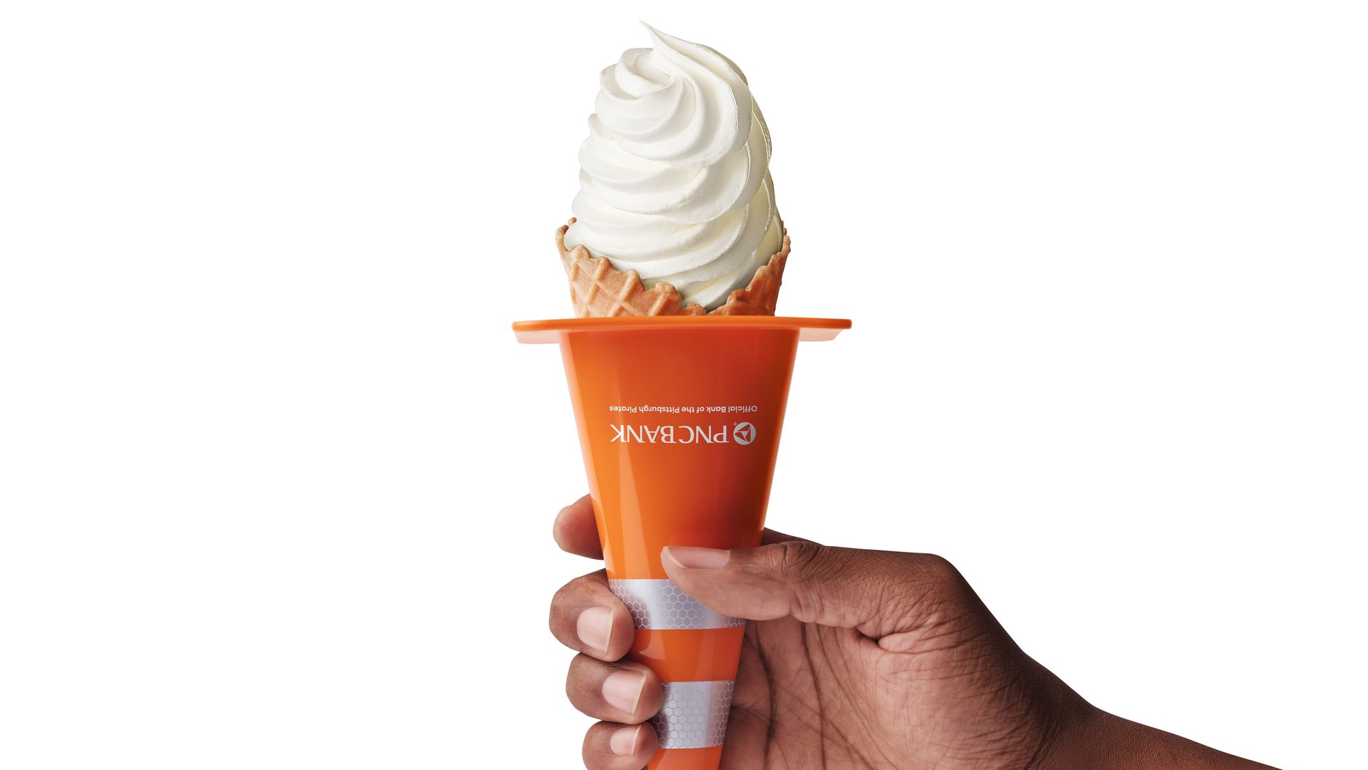 A hand holds an orange waffle cone with a tall swirl of white vanilla soft-serve against a plain white background.