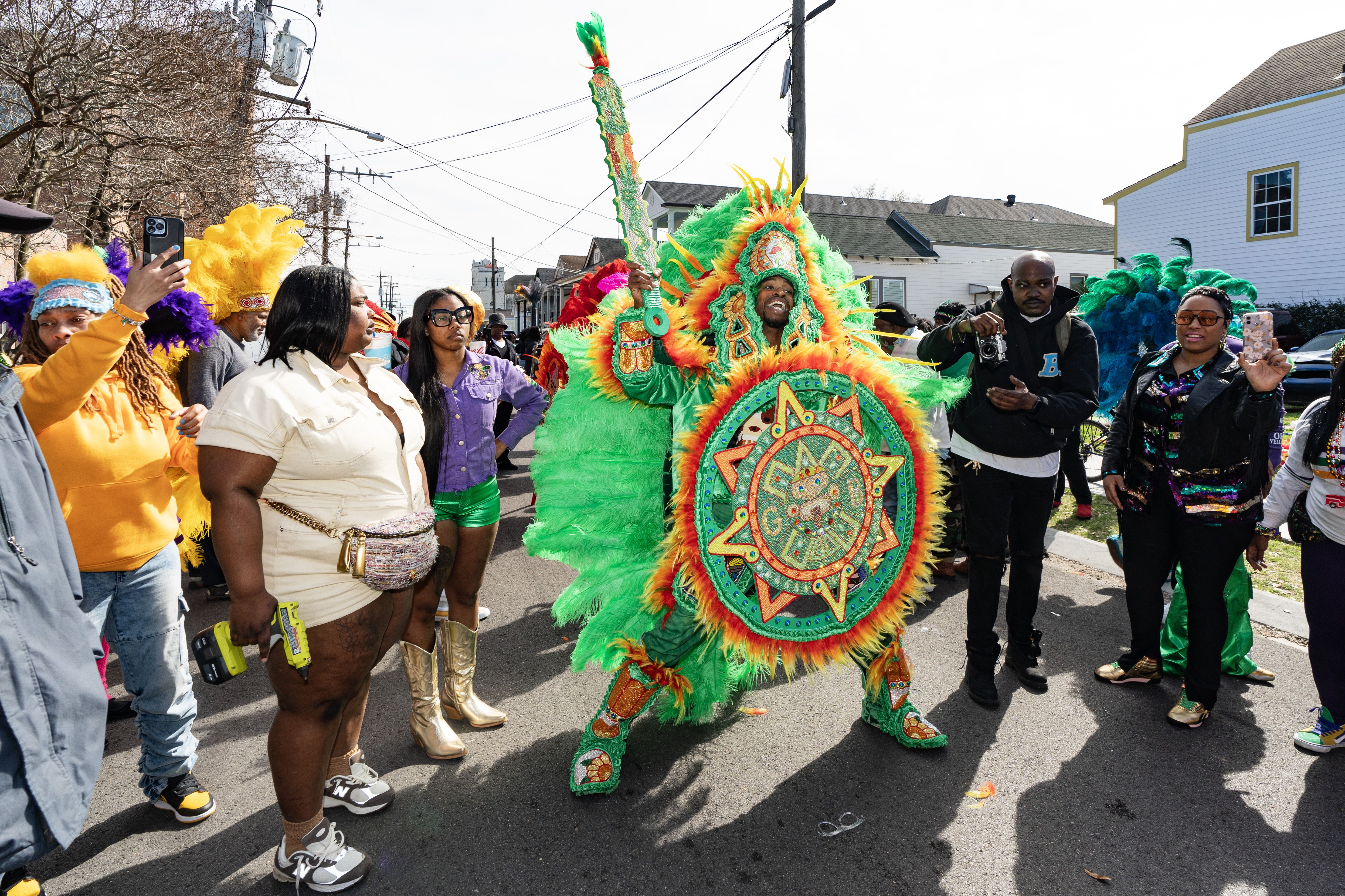 Photo shows a Mardi Gras Indian in a colorful feathered suit