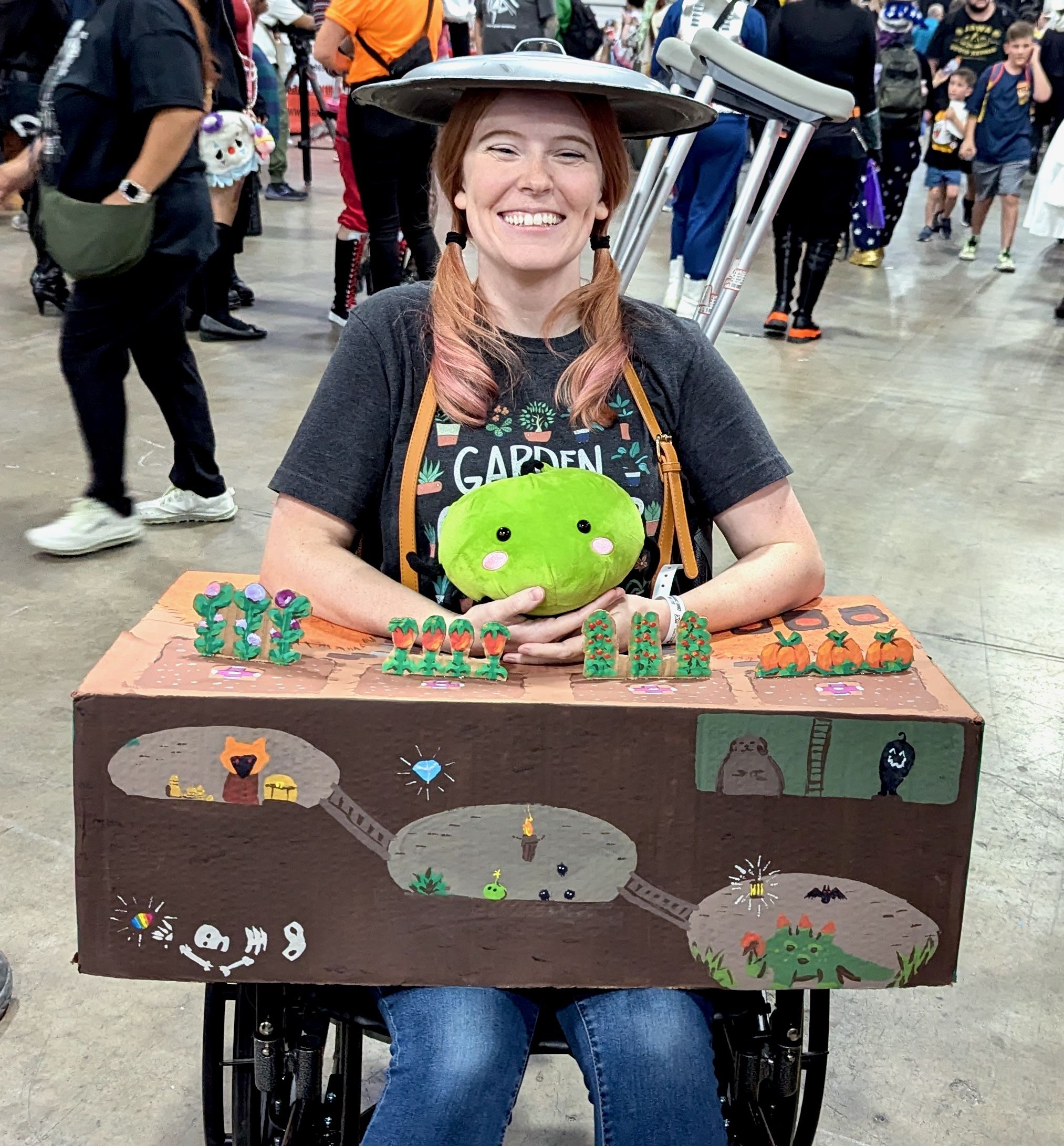 A woman with a wheelchair decorated as scenes from the video game Stardew Valley.