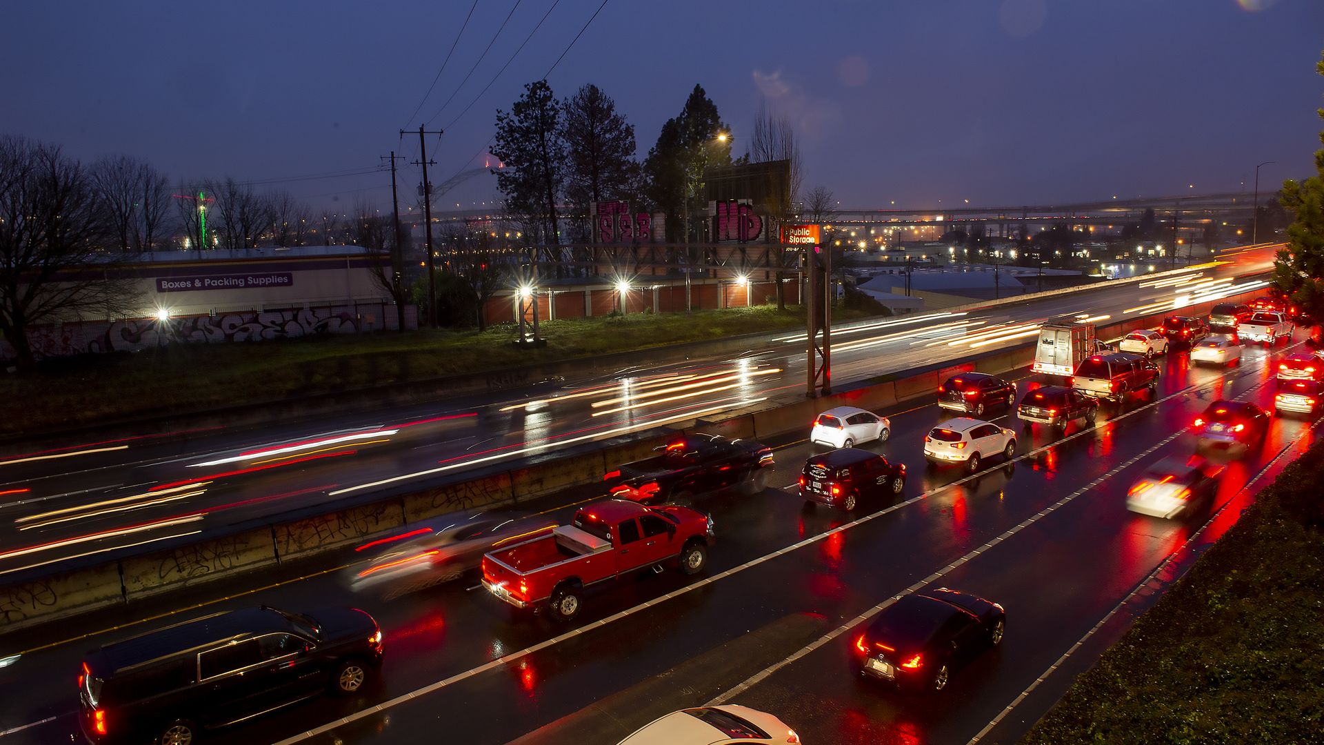A long exposure image shows cars traveling on a highway at night with headlights blurred.