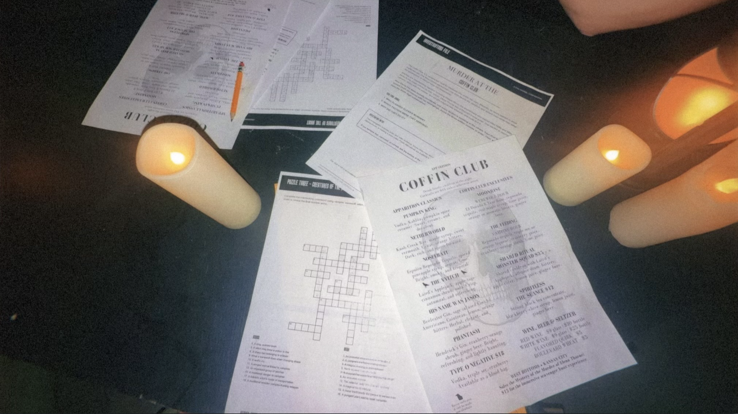 Dim table with scattered papers, a pencil, and a large "COFFIN CLUB" menu among crossword sheets. Two candles burn, casting warm orange light.