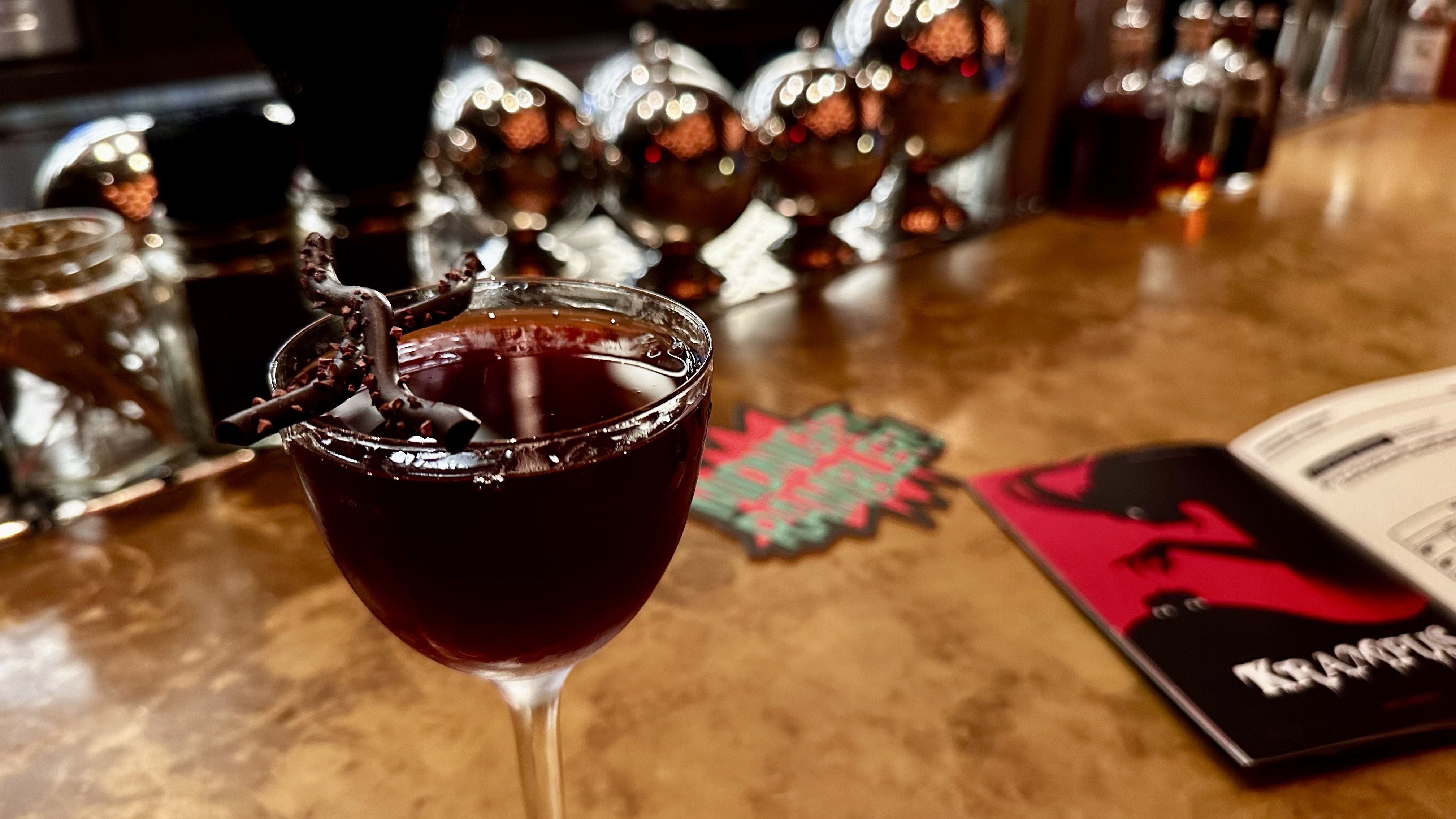 A photo of a dark colored cocktail with chocolate on top