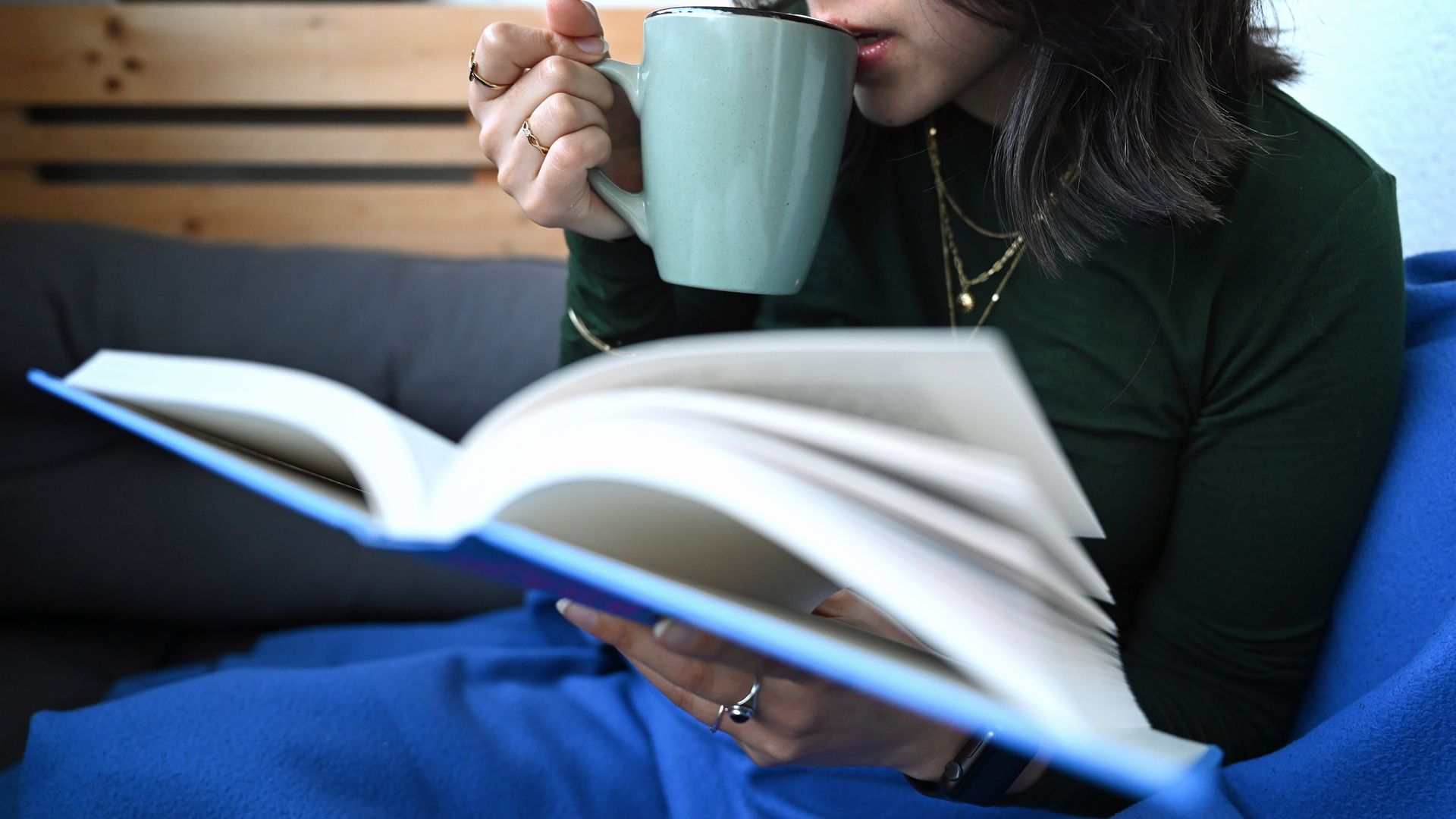 A woman sips on coffee while reading a book