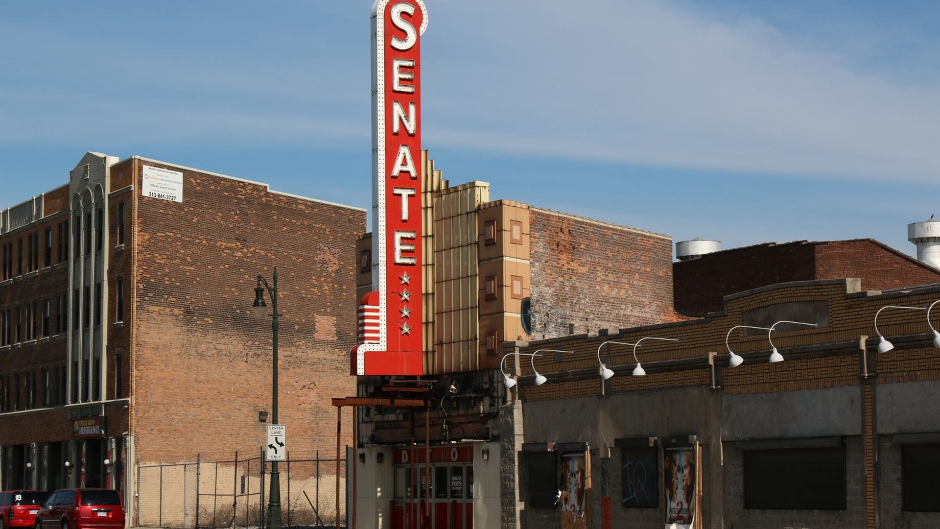 The facade of the senate theater, with a giant vertical sign that says "senate" in white letters on a red marquee