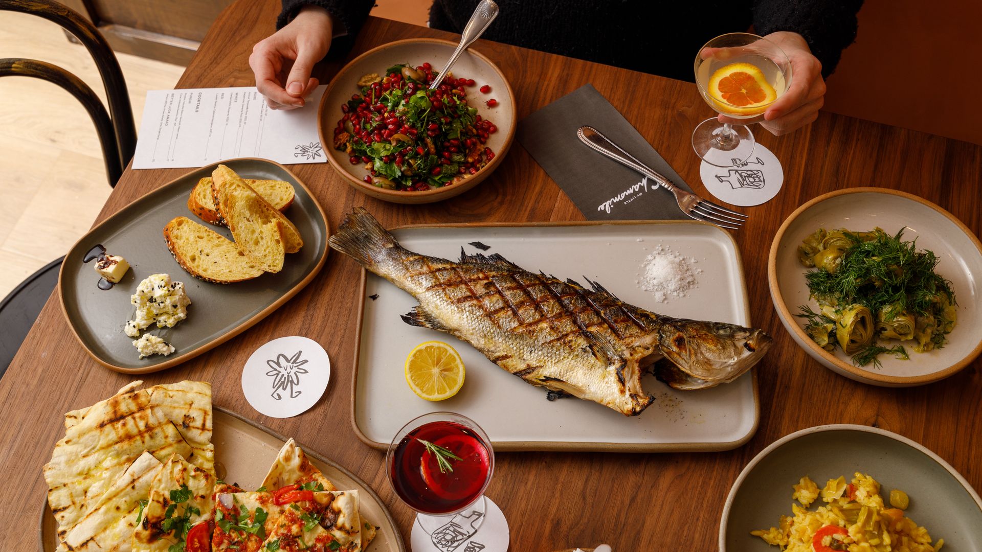 A table with a whole grilled fish, salads, lavash bread at My Little Chamomile