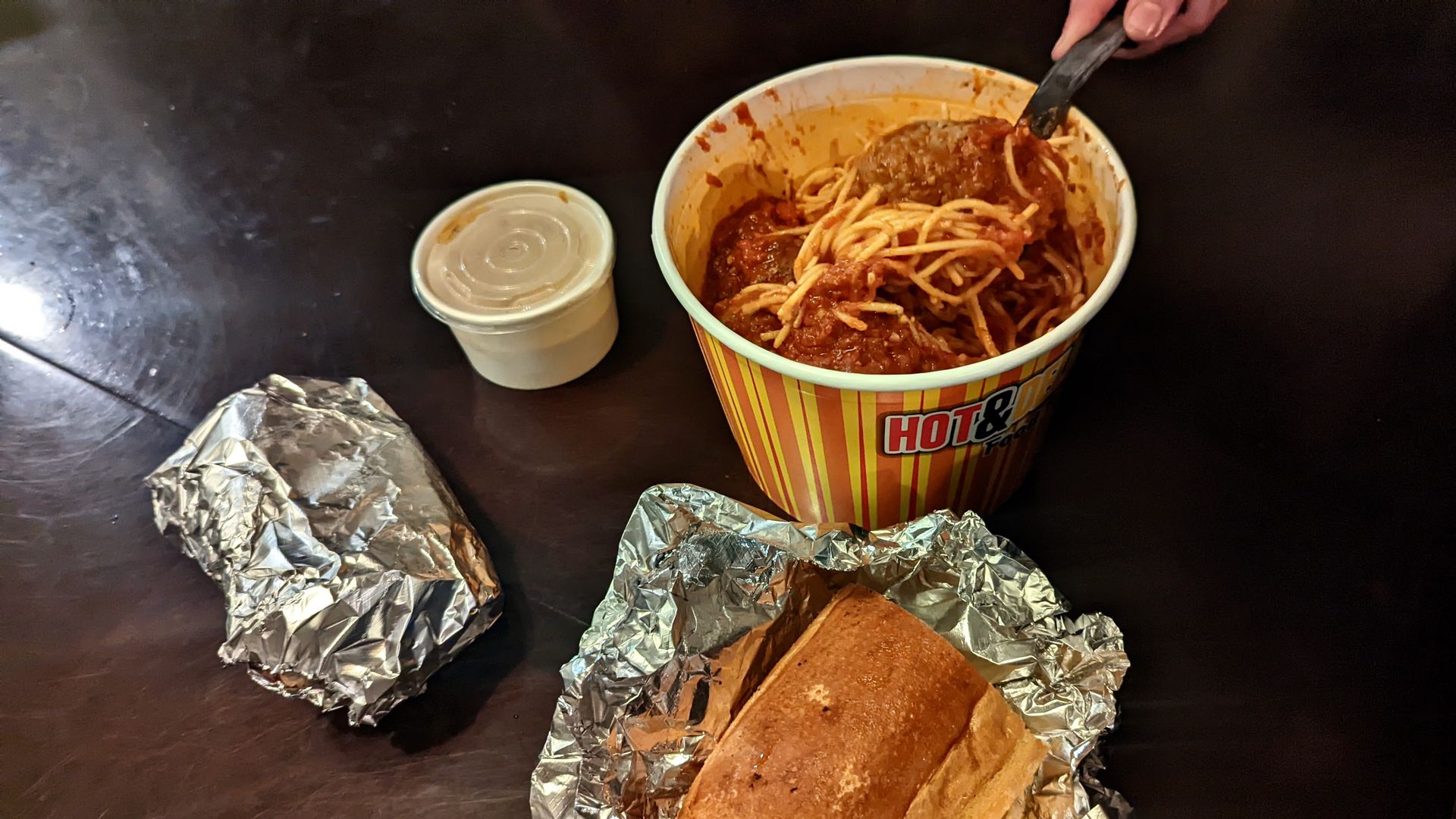A bucket of spaghetti and sauce with bread and butter.