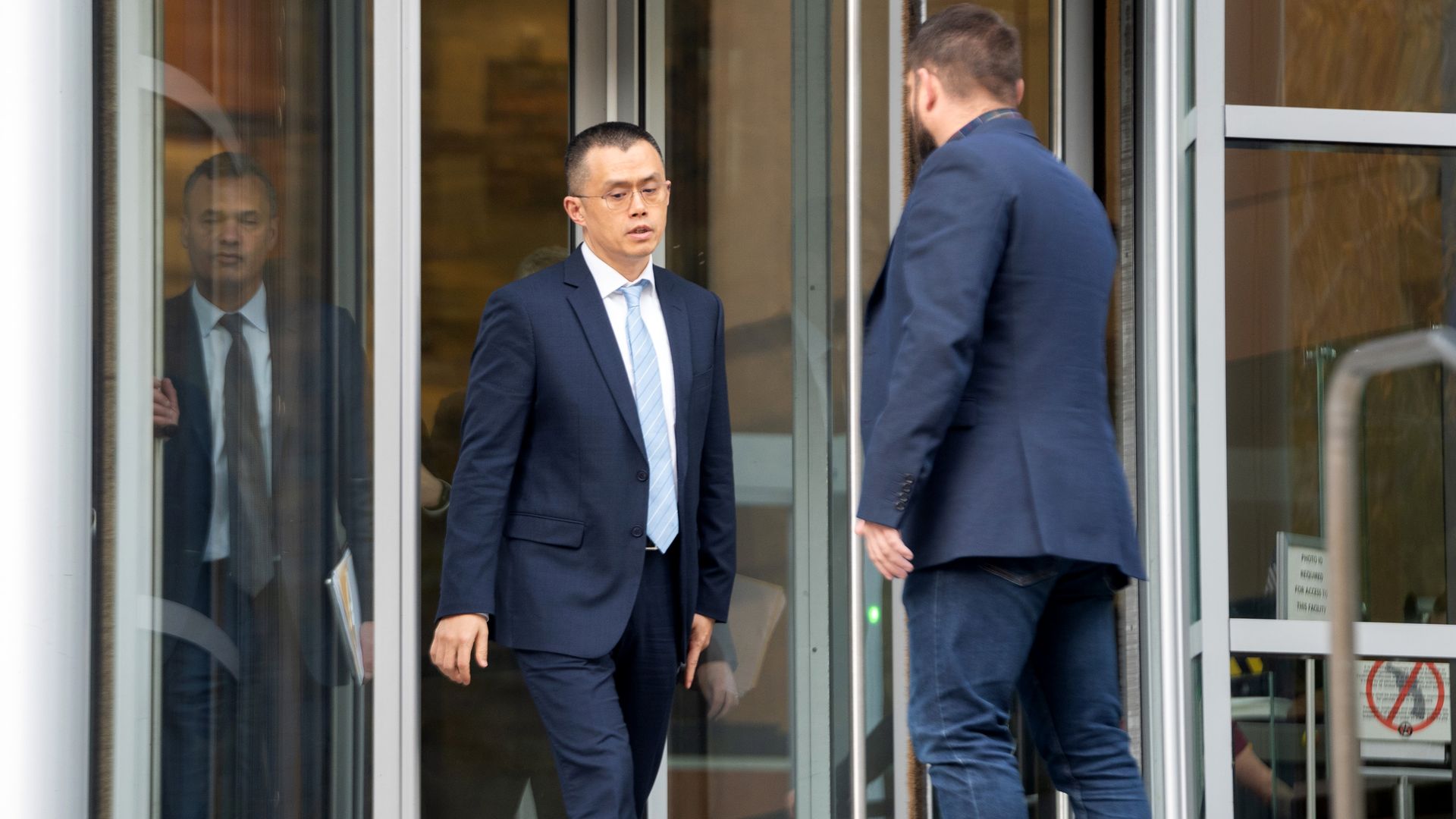A man walking out of a glass door.