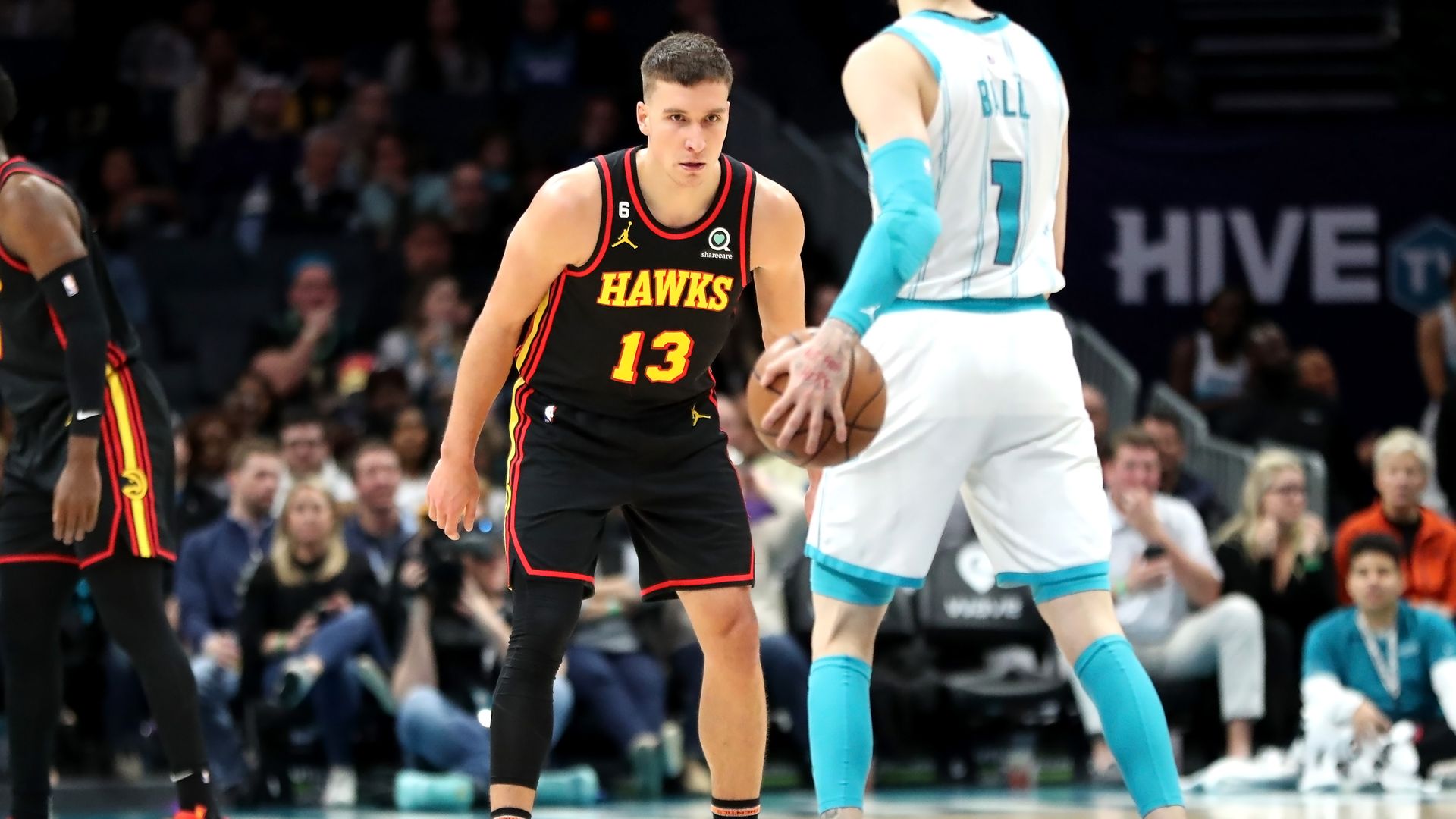 A man in a black basketball uniform that says Hawks stares ahead