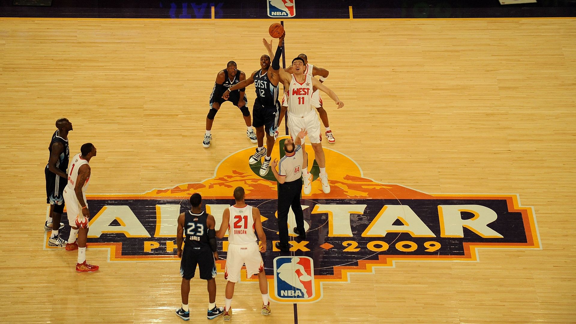 A basketball tip off on a court that says "All-Star Phoenix 2009."