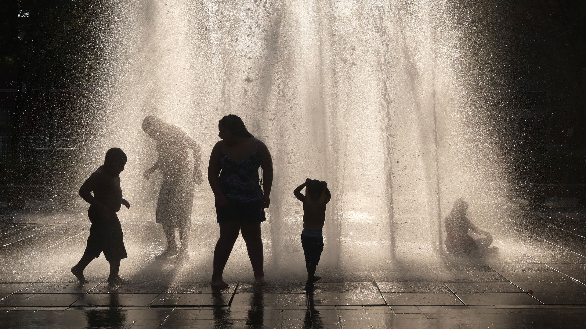 People walking through a fountain at dusk in Hobroken, New Jersey, on June 29.