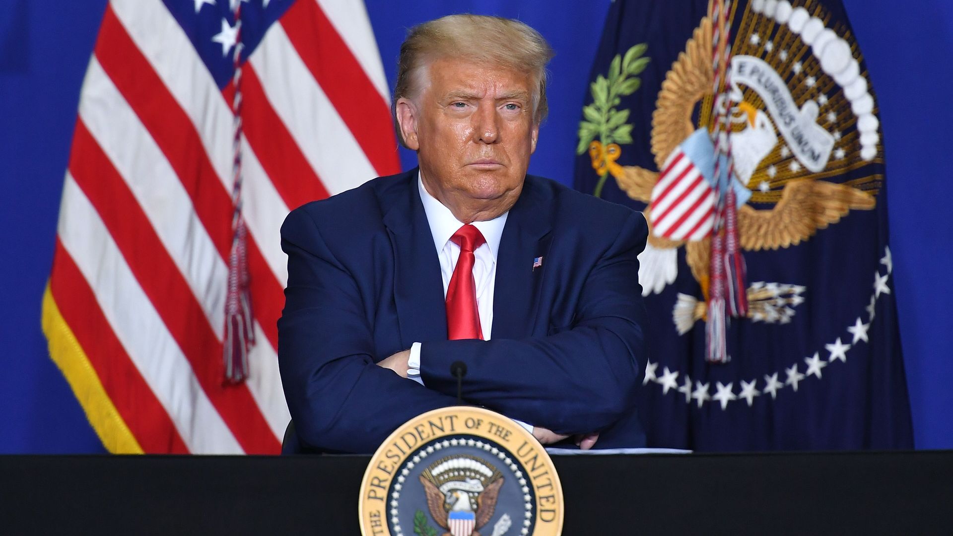 Trump sits with his arms folded