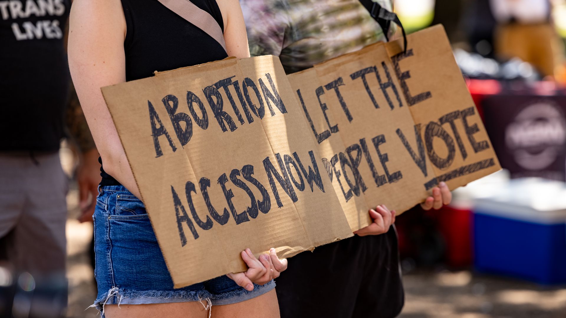 Woman holds protest sign written on cardboard