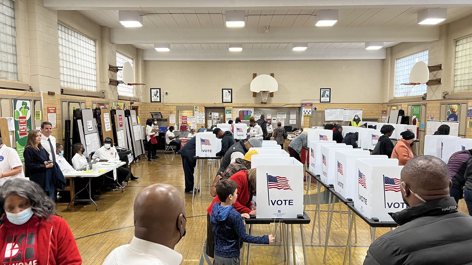 Voters, including Secretary of State Jocelyn Benson (red coat) with her son, cast ballots inside Pasteur Elementary school on Nov. 8. Photo: Samuel Robinson/Axios