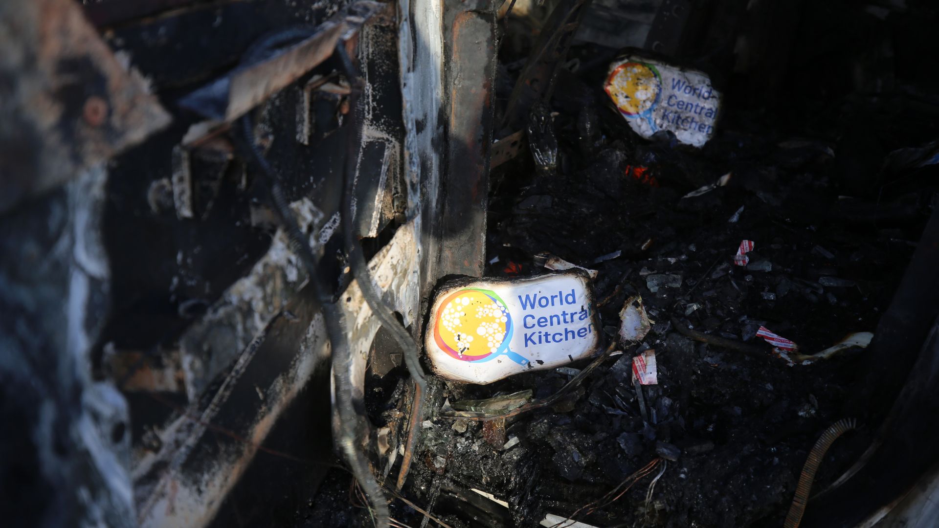 A burned out car with several white "World Central Kitchen" logos.