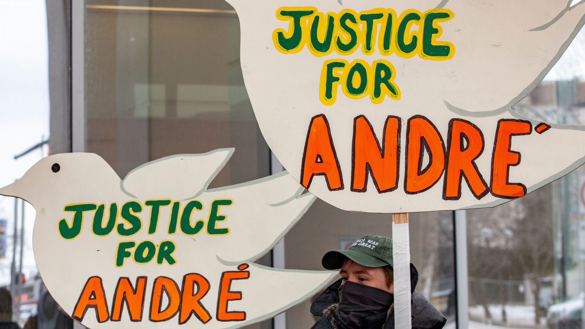 Photo of a person holding a large sign in the shape of a bird, with the words "Justice for Andre"