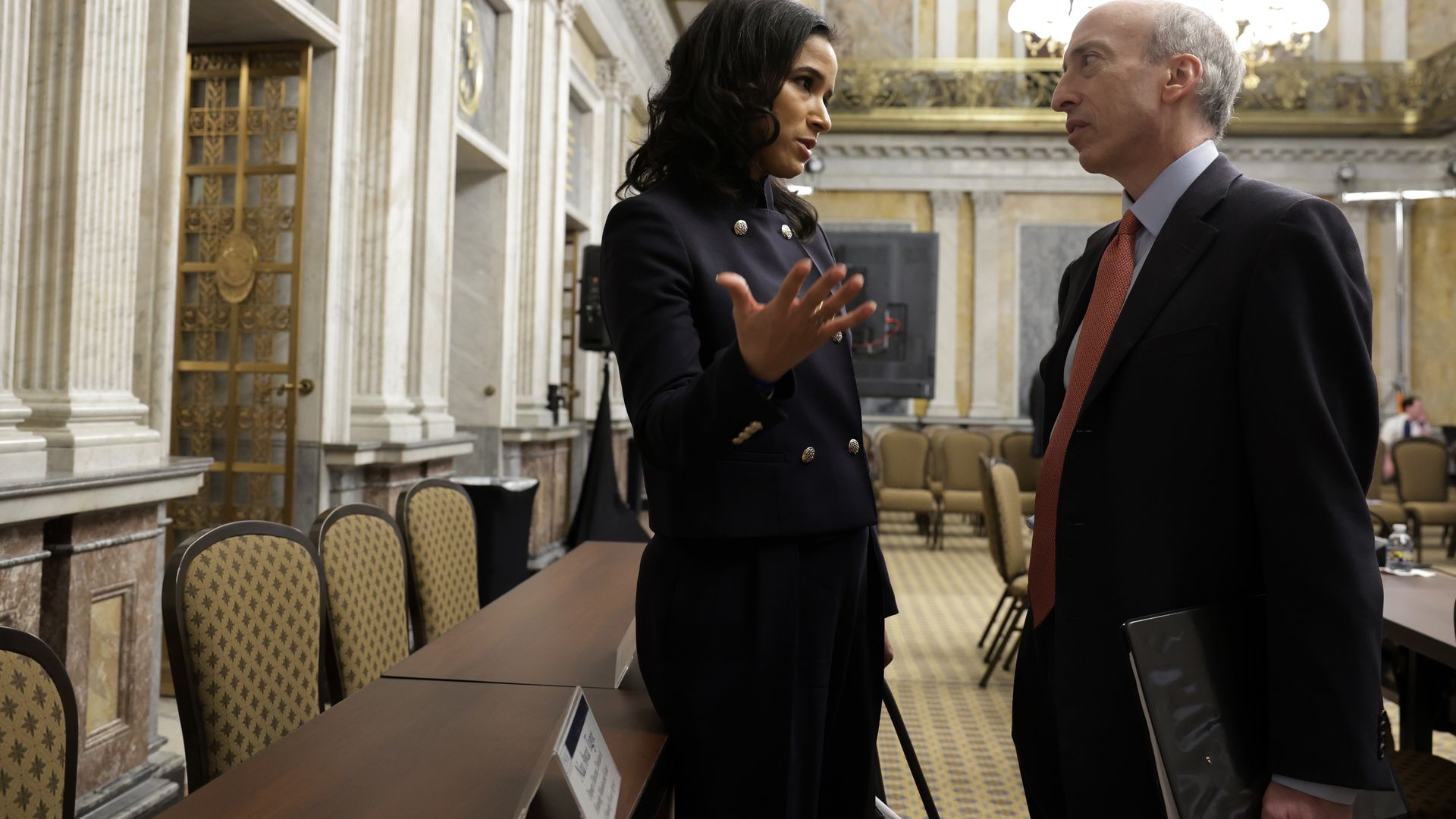 Male and female government officials have a private one-on-one following a hearing in an official looking room. 