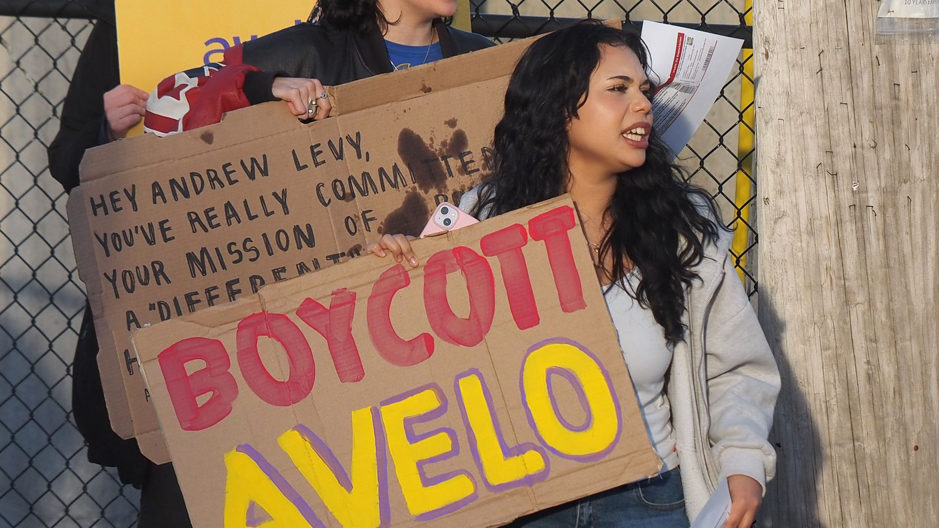 Person holds a cardboard sign that says "BOYCOTT AVELO"