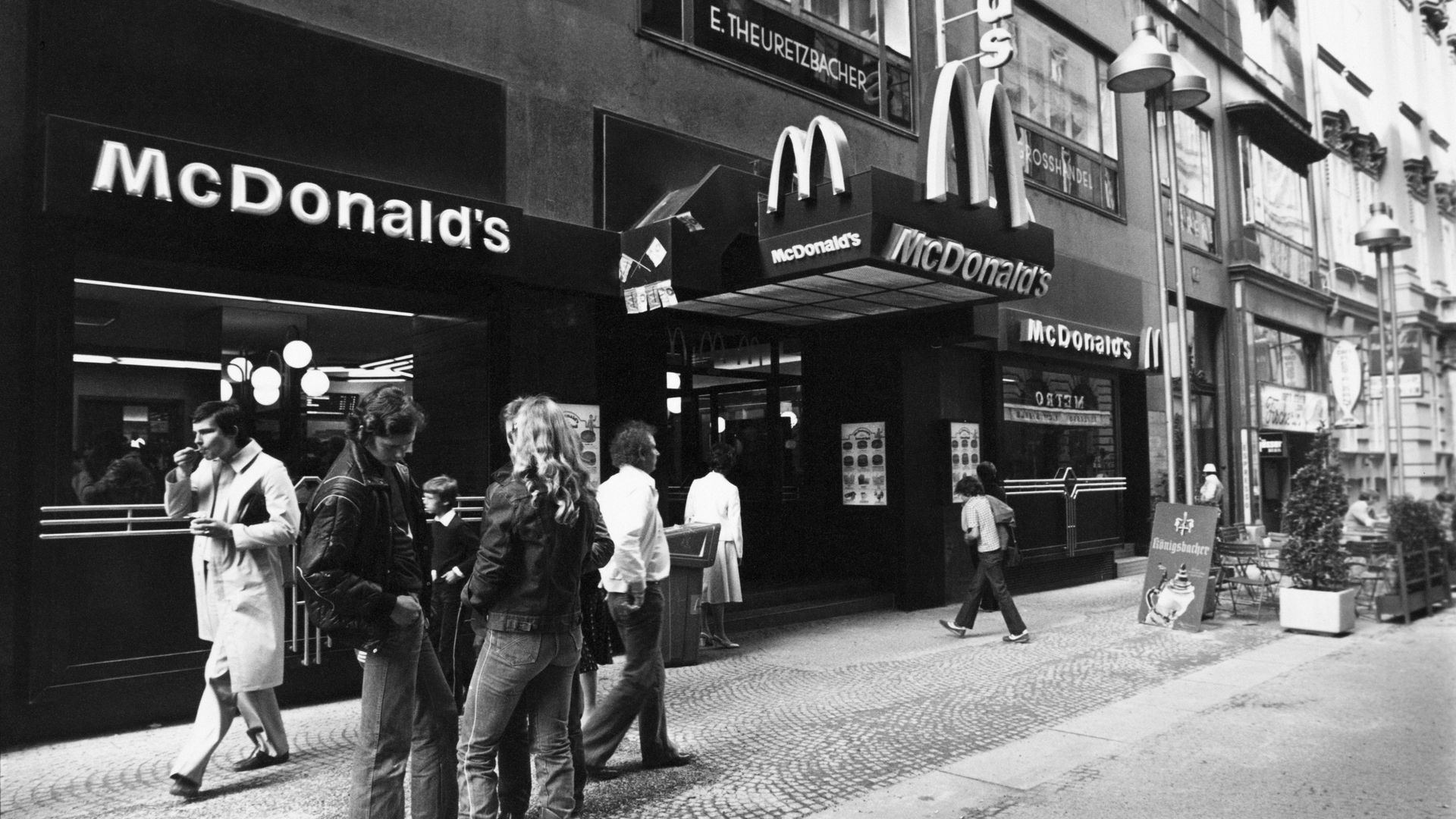 A group of people stand outside McDonald's in a black and white photo