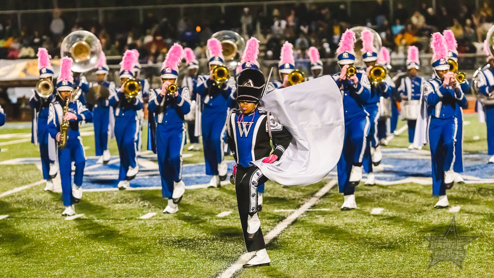A photo of a marching band with brass instruments and a bandleader leading out front 