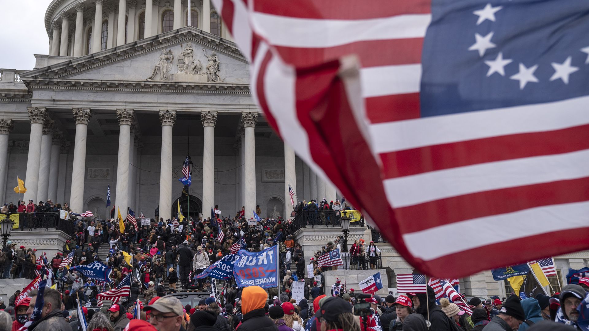 Photo of Trump supporters crowded onto the U.S. Capitol as an American flag flies in the foreground