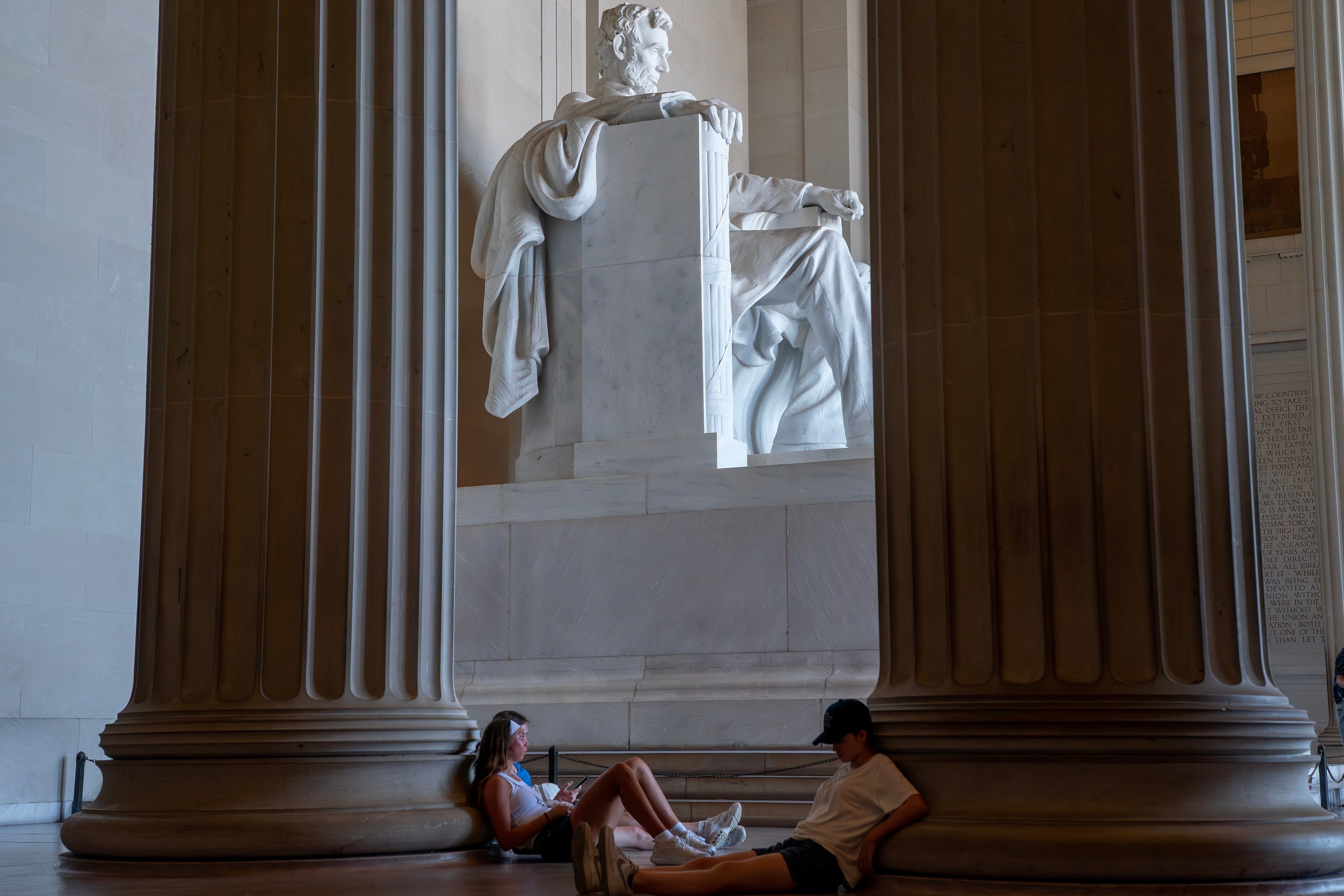 Visitors rest in the shade of the Lincoln Memorial on the National Mall during an extreme heat advisory, Thursday, July 2, 2026, in Washington. (AP Photo/Nathan Howard)
