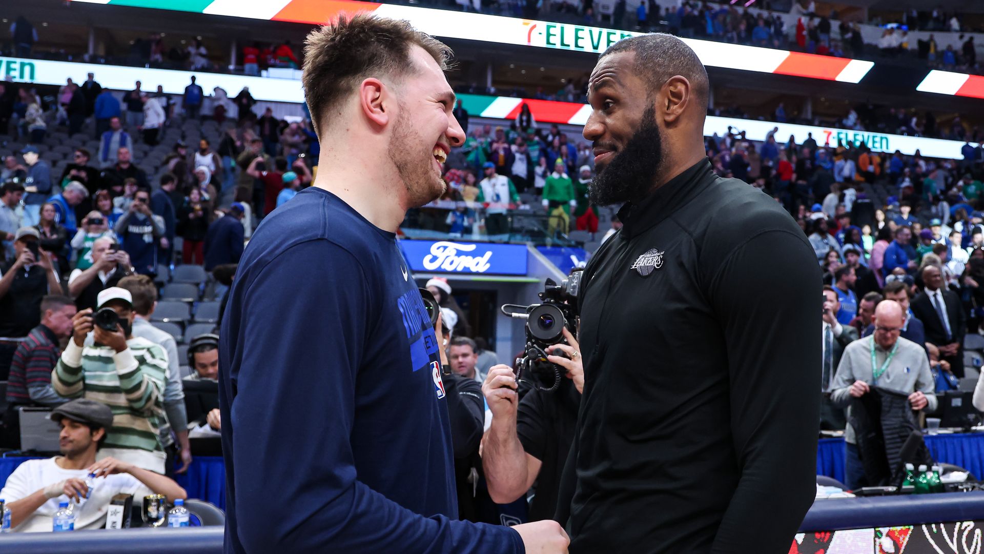Two basketball players stand facing each other, smiling