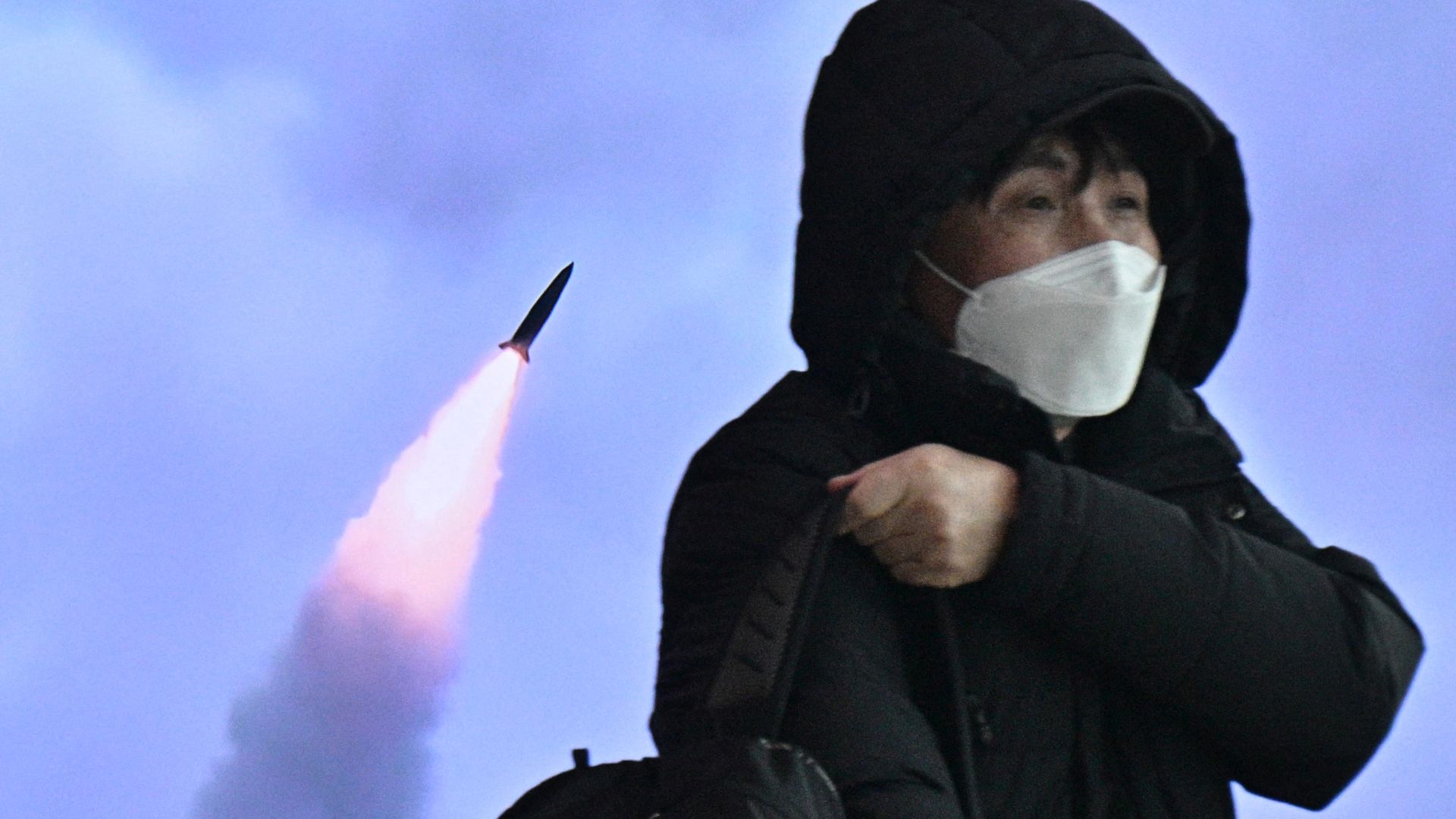A man walks past a television screen showing a news broadcast with file footage of a North Korean missile test, at a railway station in Seoul on March 16.