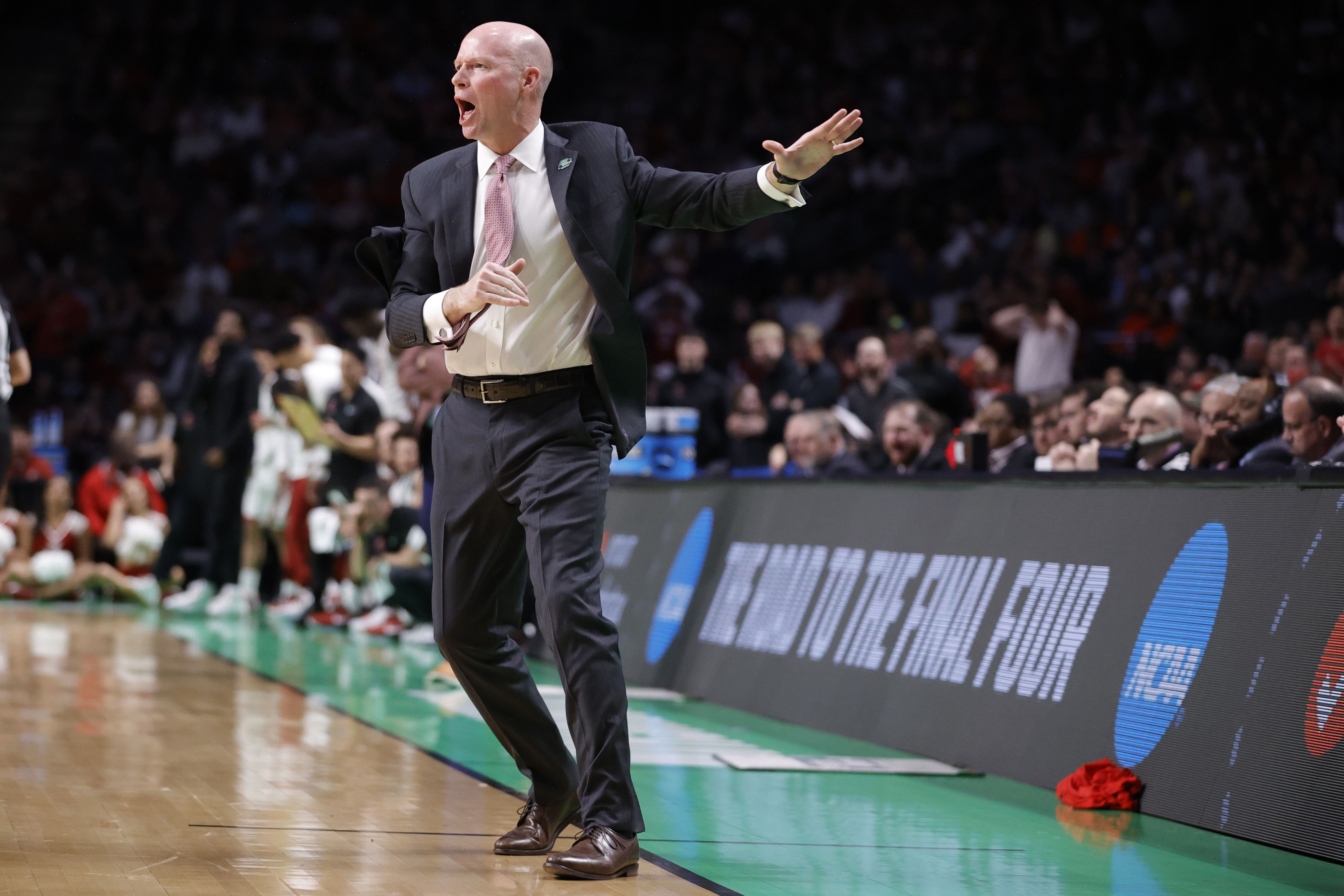 Photo of a coach on the sidelines of a basketball court.