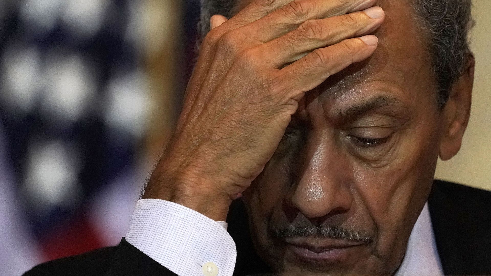 In this image, former congressman Mel Watt looks down and away from the camera, partially covering his face with one hand.