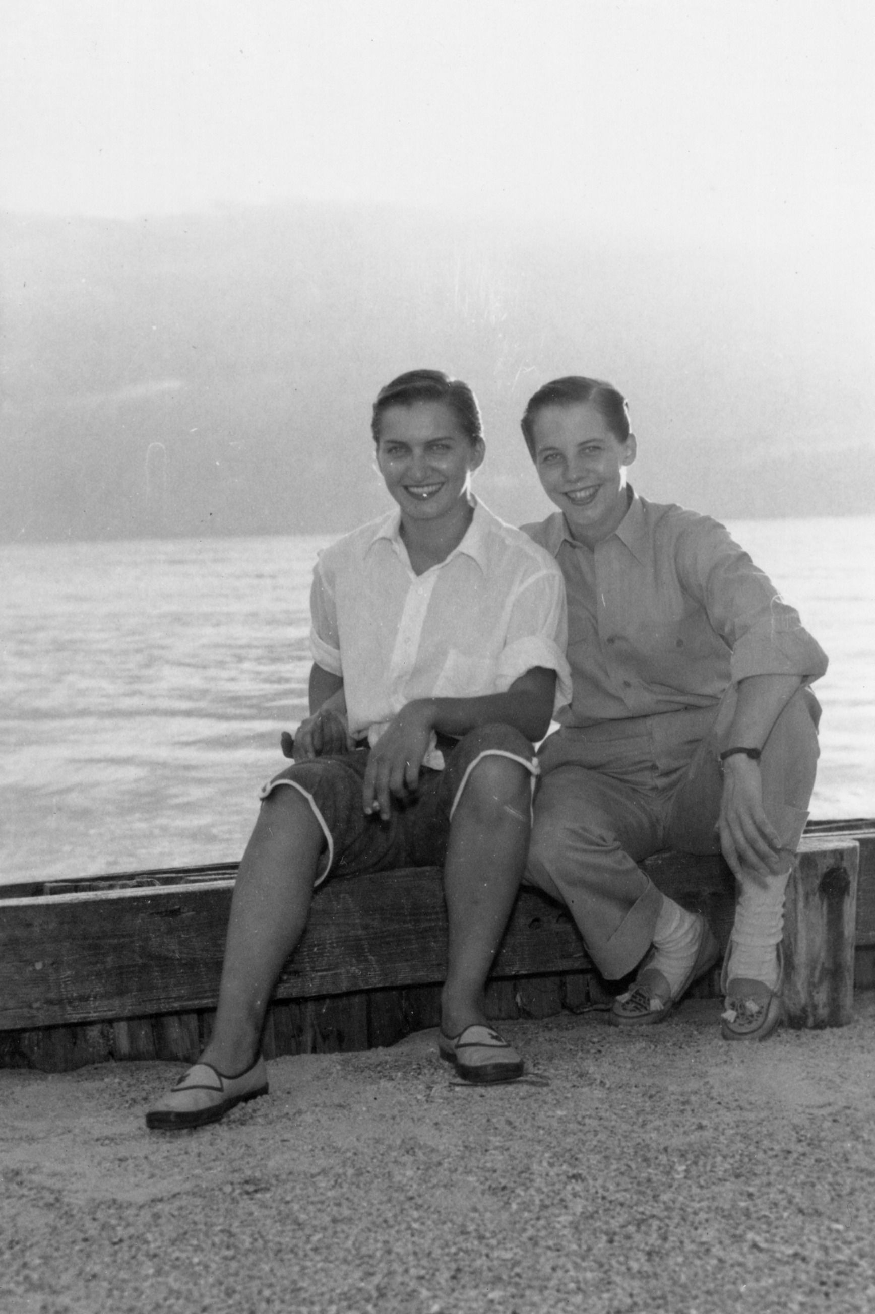 a black and white photo of a couple at the beach smiling