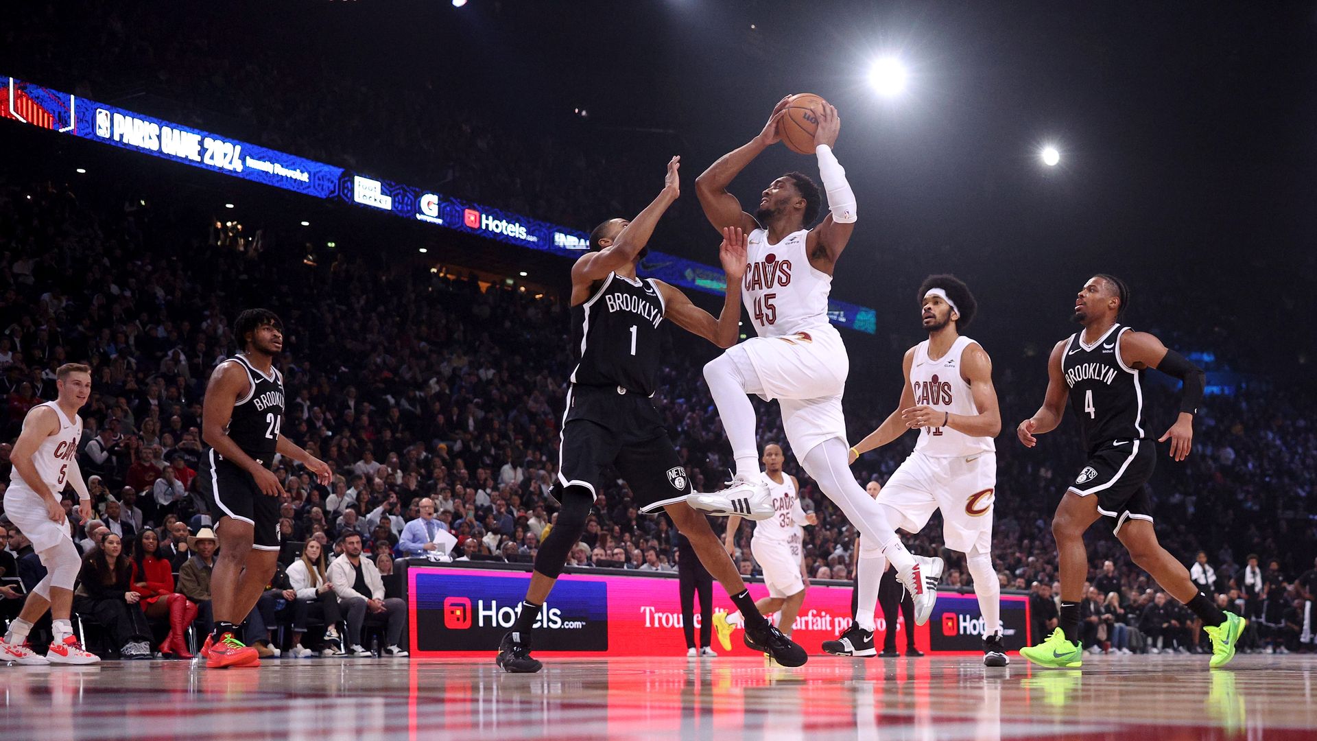 Donovan Mitchell (white jersey) drives to the hoop against the Brooklyn Nets (black jerseys) 
