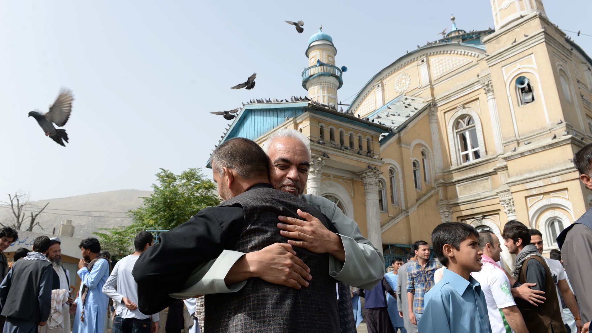 Men hug in front of a mosque in Kabul