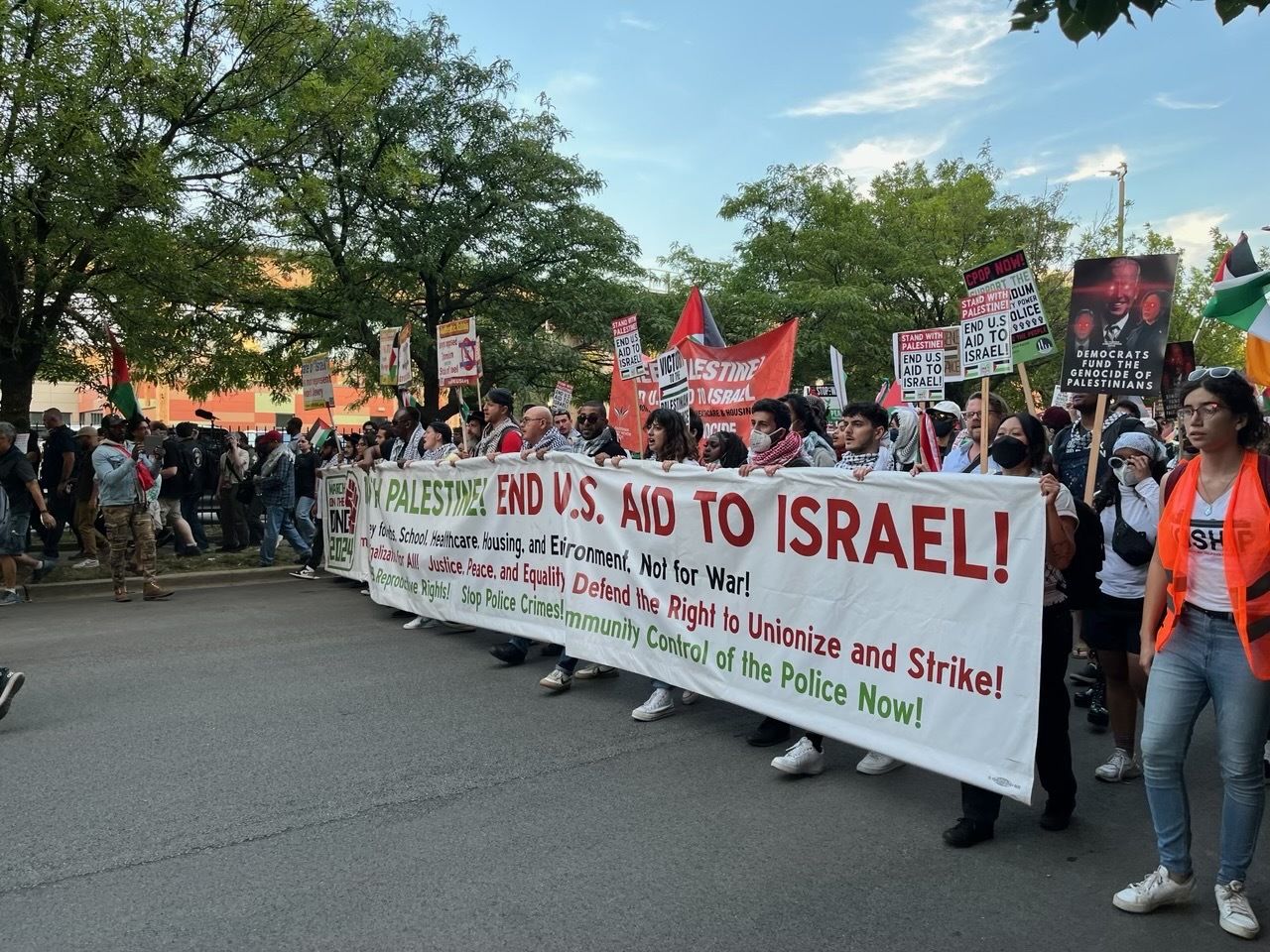 Photo of protesters holding a banner as they march on a street 