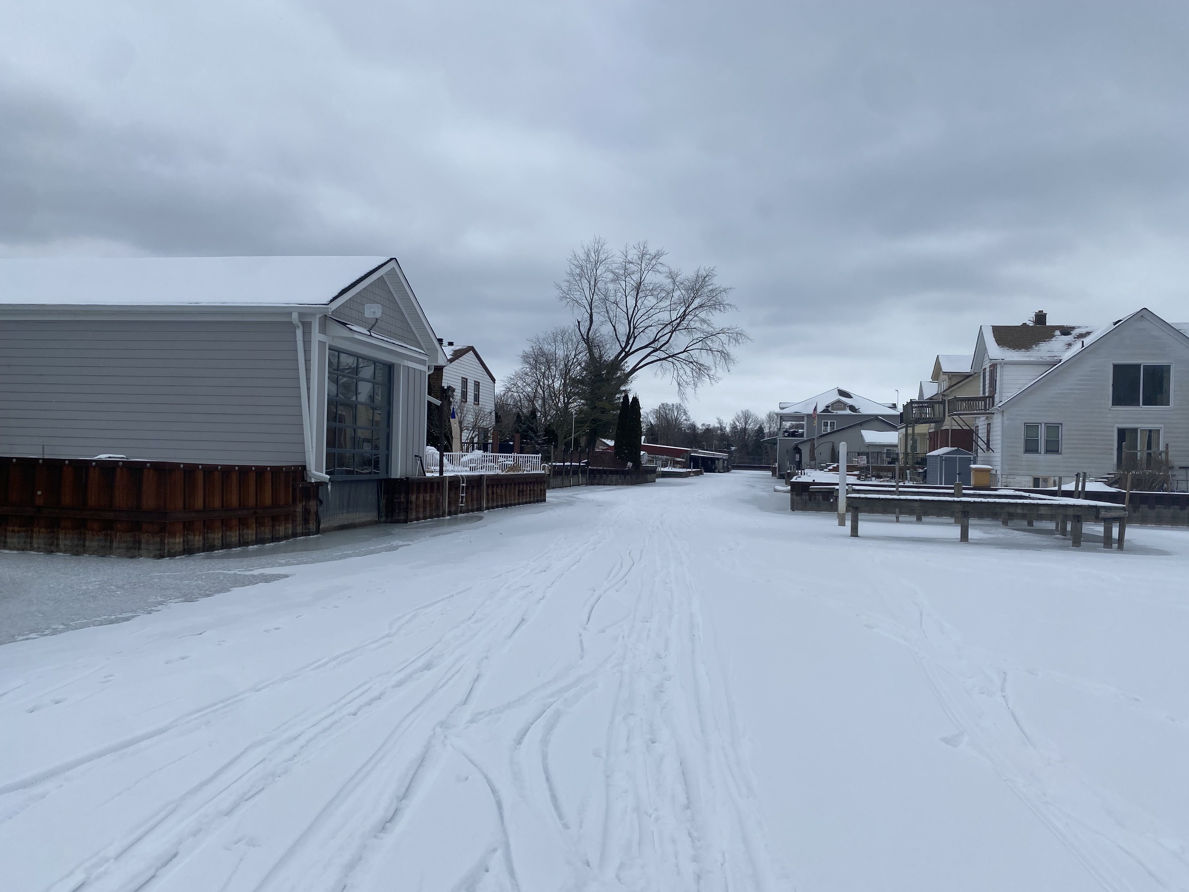 Houses and garages along the canal. Deep tracks in the snow. 